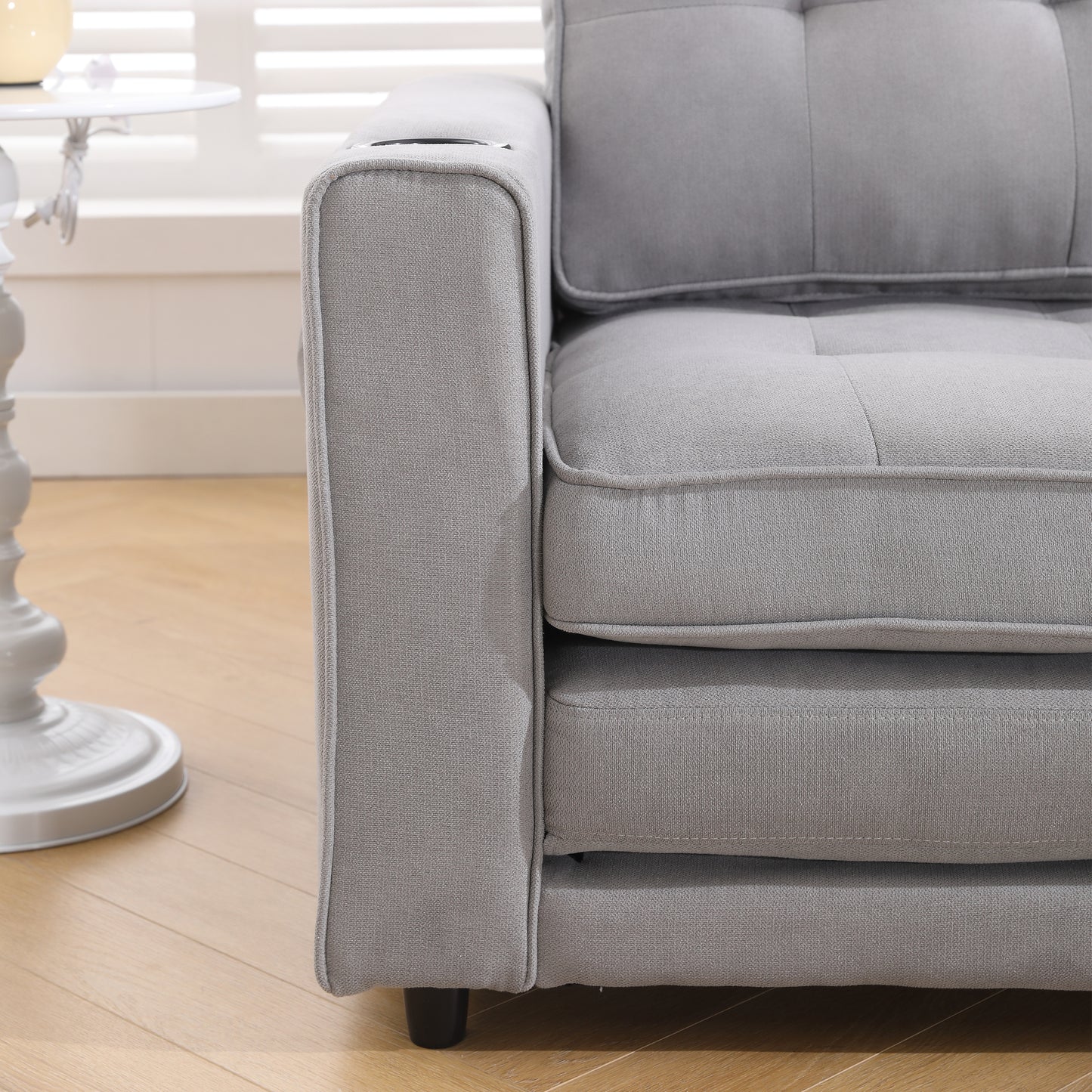 Closeup of a modern grey fabric sofa with plush cushioning and a builtin cup holder
