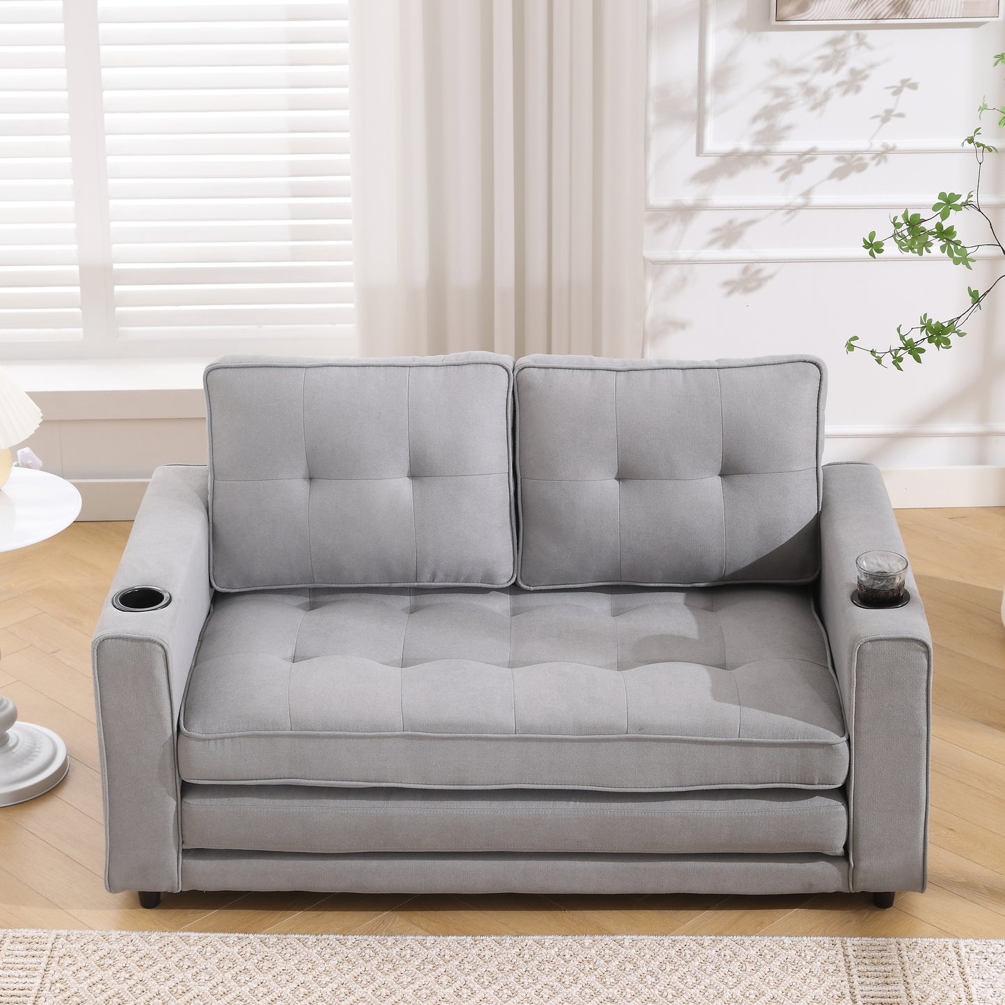 Gray upholstered loveseat with tufted cushions and builtin cup holders perfect for small spaces