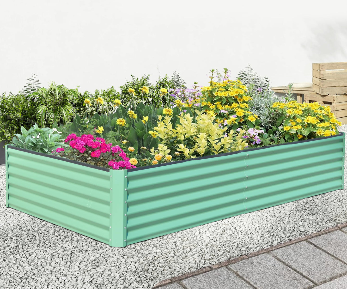 Green corrugated metal raised garden bed filled with vibrant pink and yellow flowers