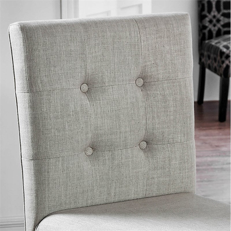 Closeup of a grey linen upholstered dining chair with button tufting