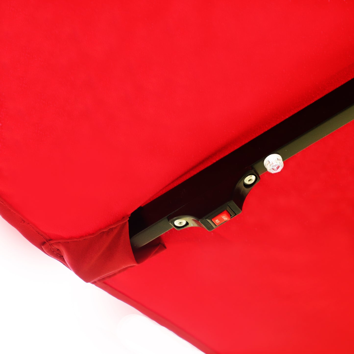 Closeup of a red patio umbrella canopy with an integrated onoff switch for lights