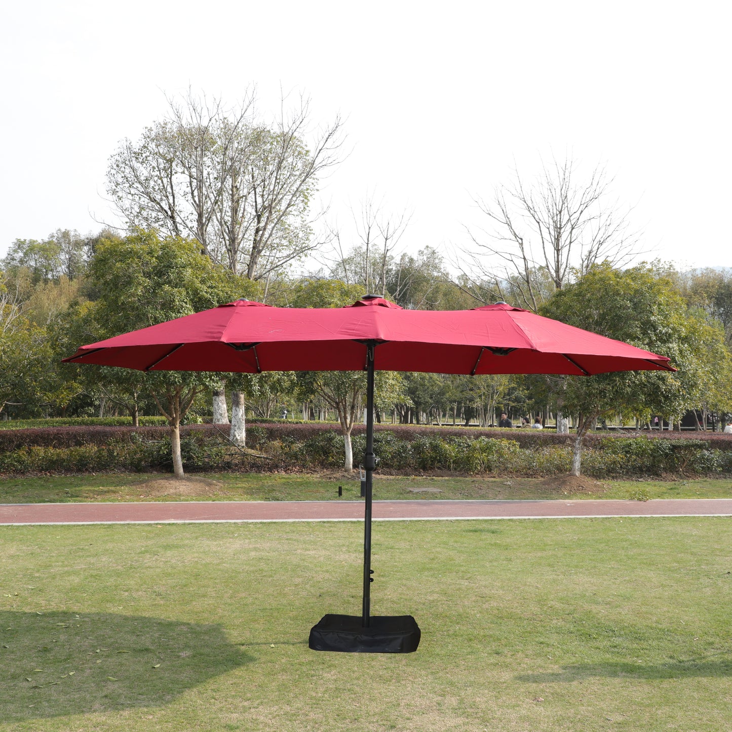 Large red double patio umbrella open on a grassy lawn perfect for outdoor events
