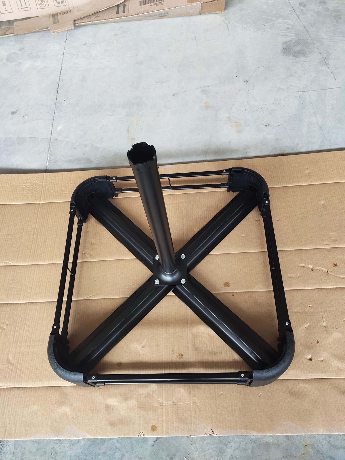 Black metal umbrella base frame with a central pole ideal for patio outdoor use