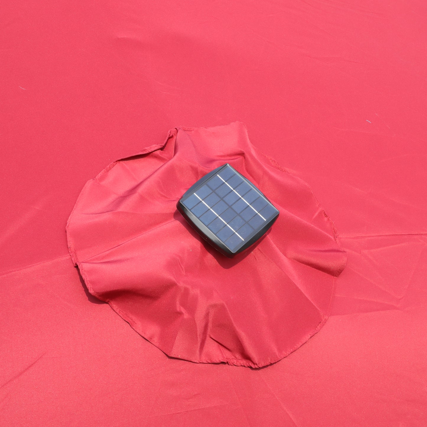 Red patio umbrella fabric detail with integrated solar panel for lighting