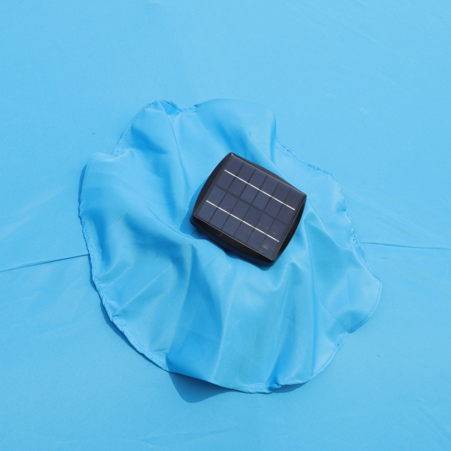 Compact solar panel with black frame powering outdoor lights or devices on a blue fabric surface