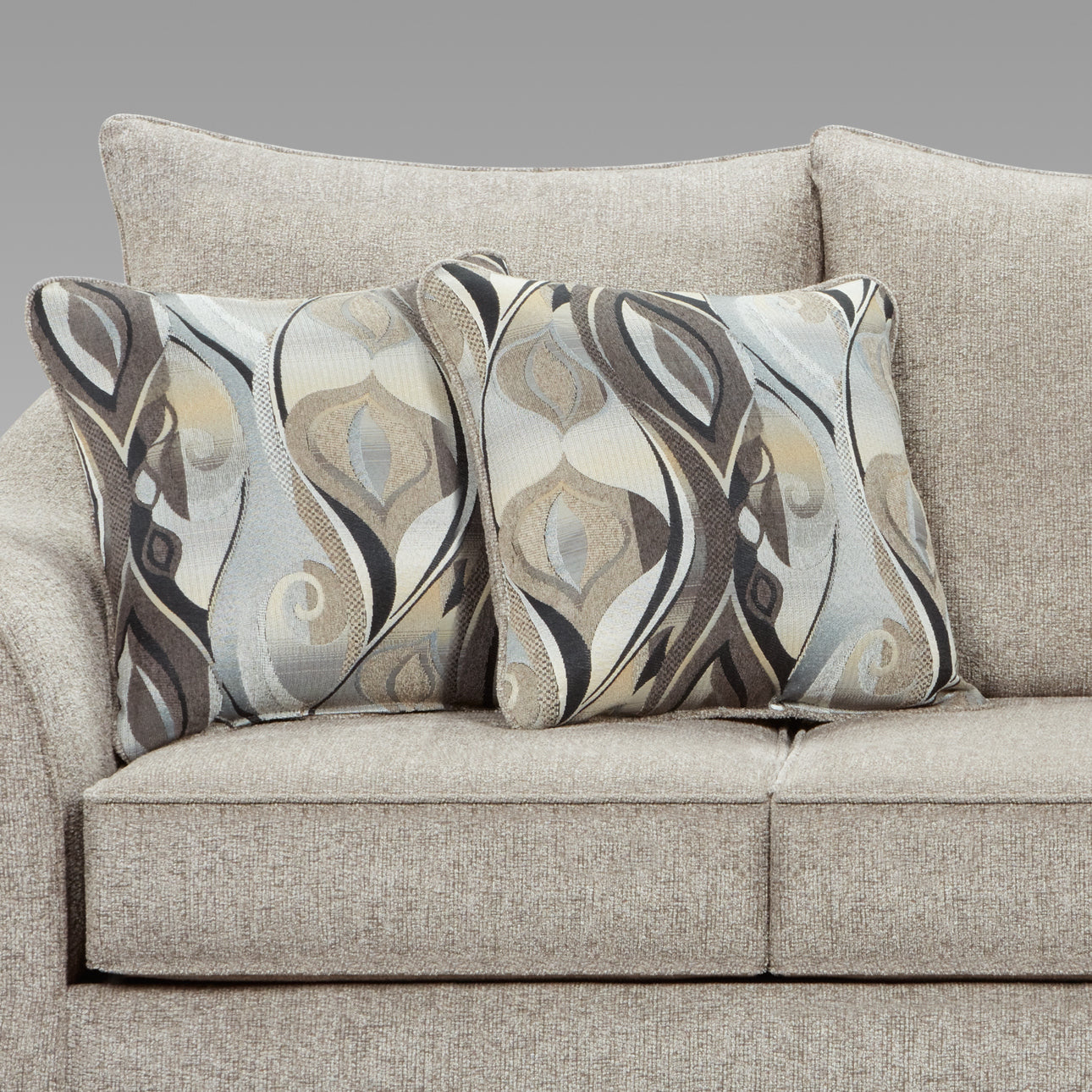 Two decorative throw pillows with abstract grey and beige patterns rest on a neutral textured sofa