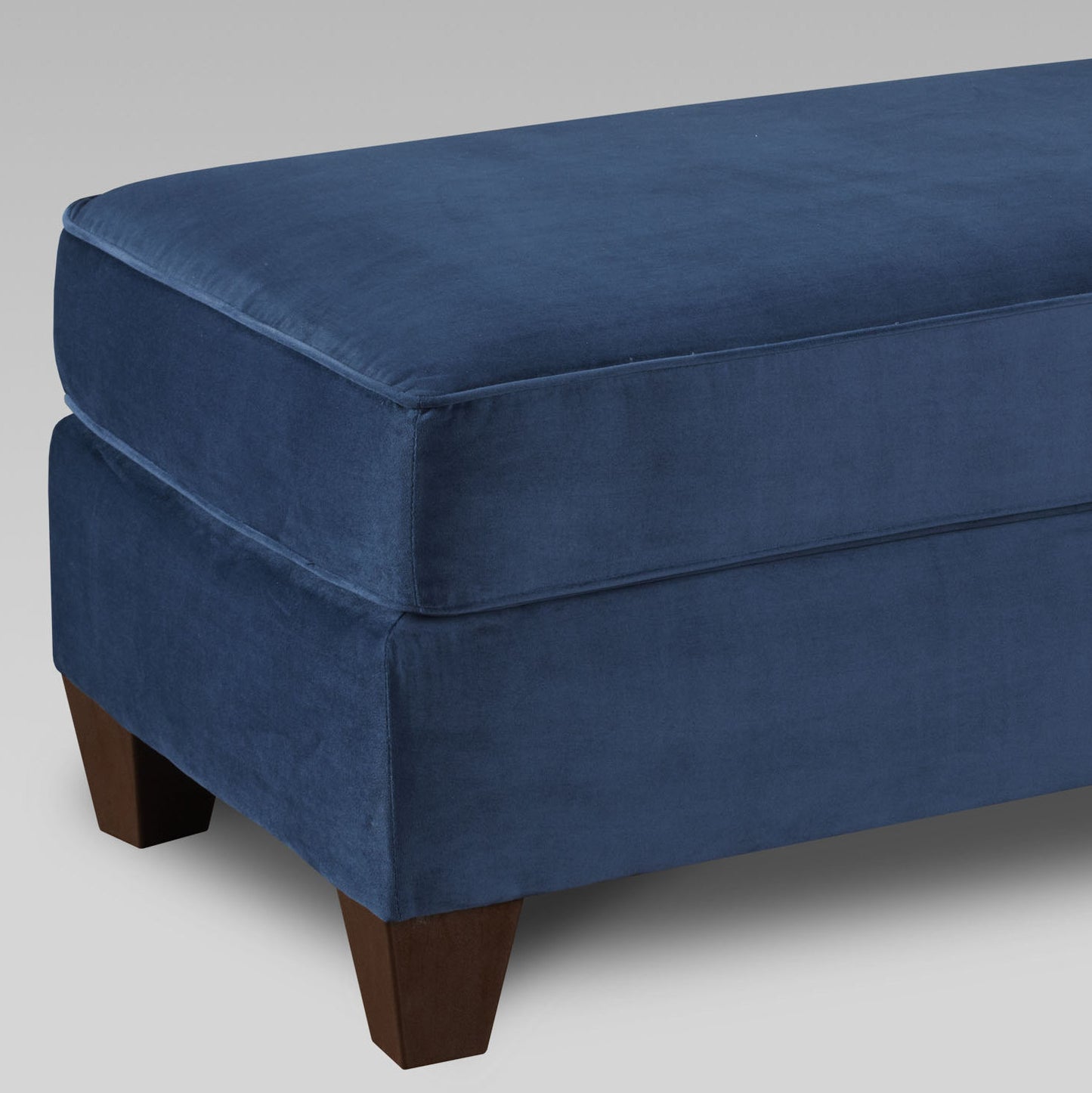 Deep blue velvet ottoman with cushioned top and dark wood legs