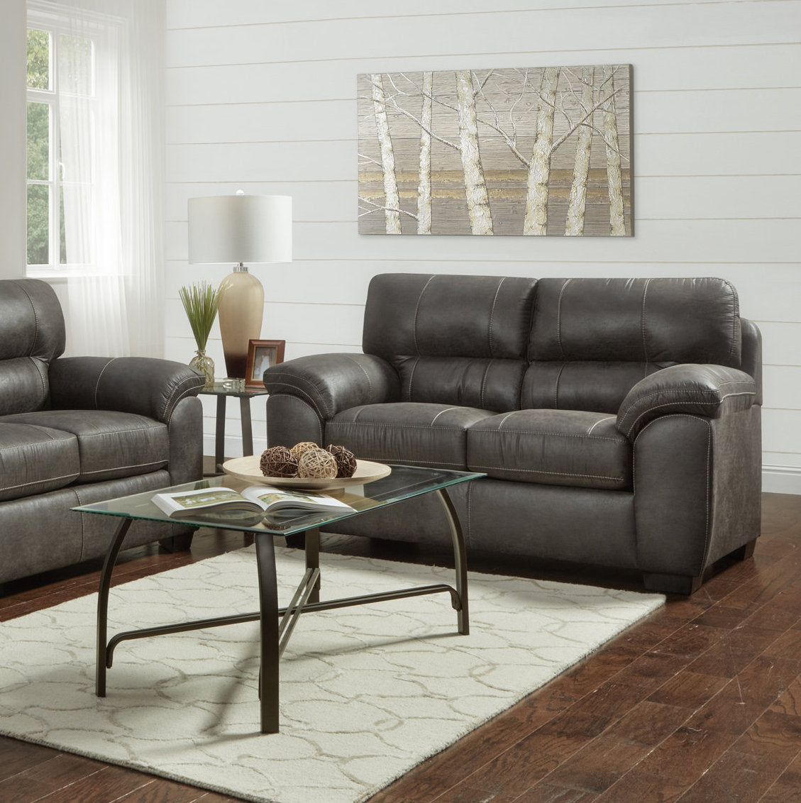 Gray leather loveseat with stitching details and plush cushions perfect for a living room