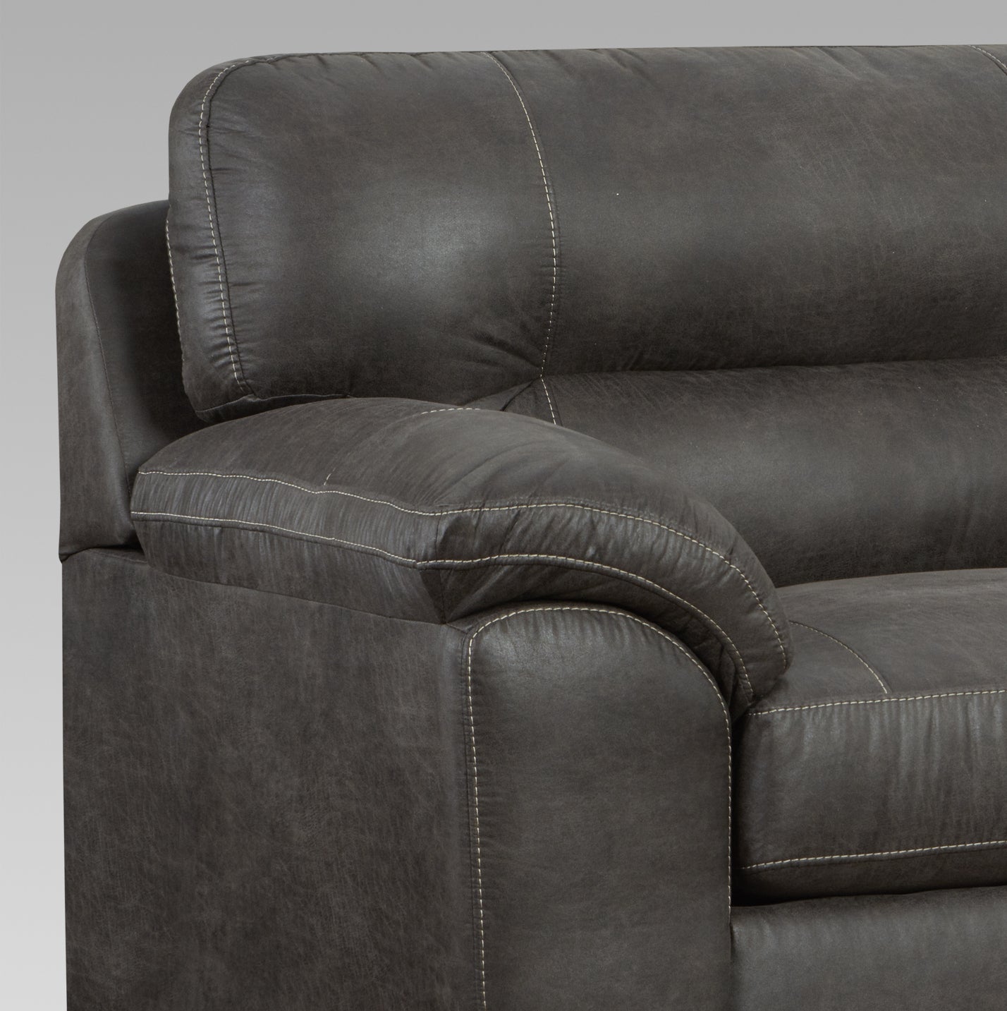 Closeup of a dark gray faux leather sofa arm with contrasting cream stitching