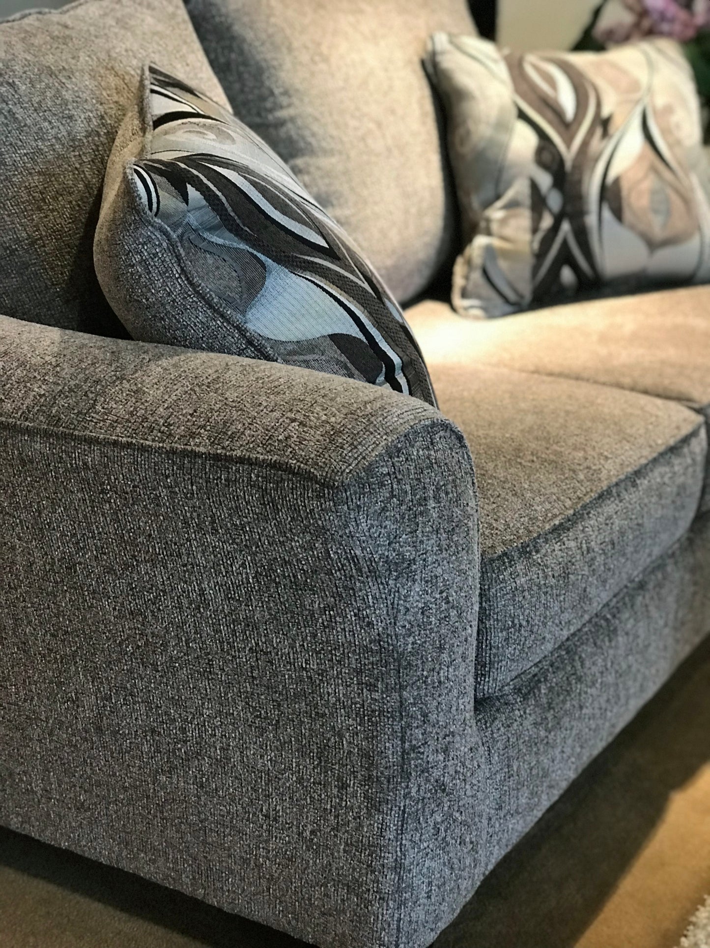 Grey fabric sofa with modern geometric pattern accent pillow