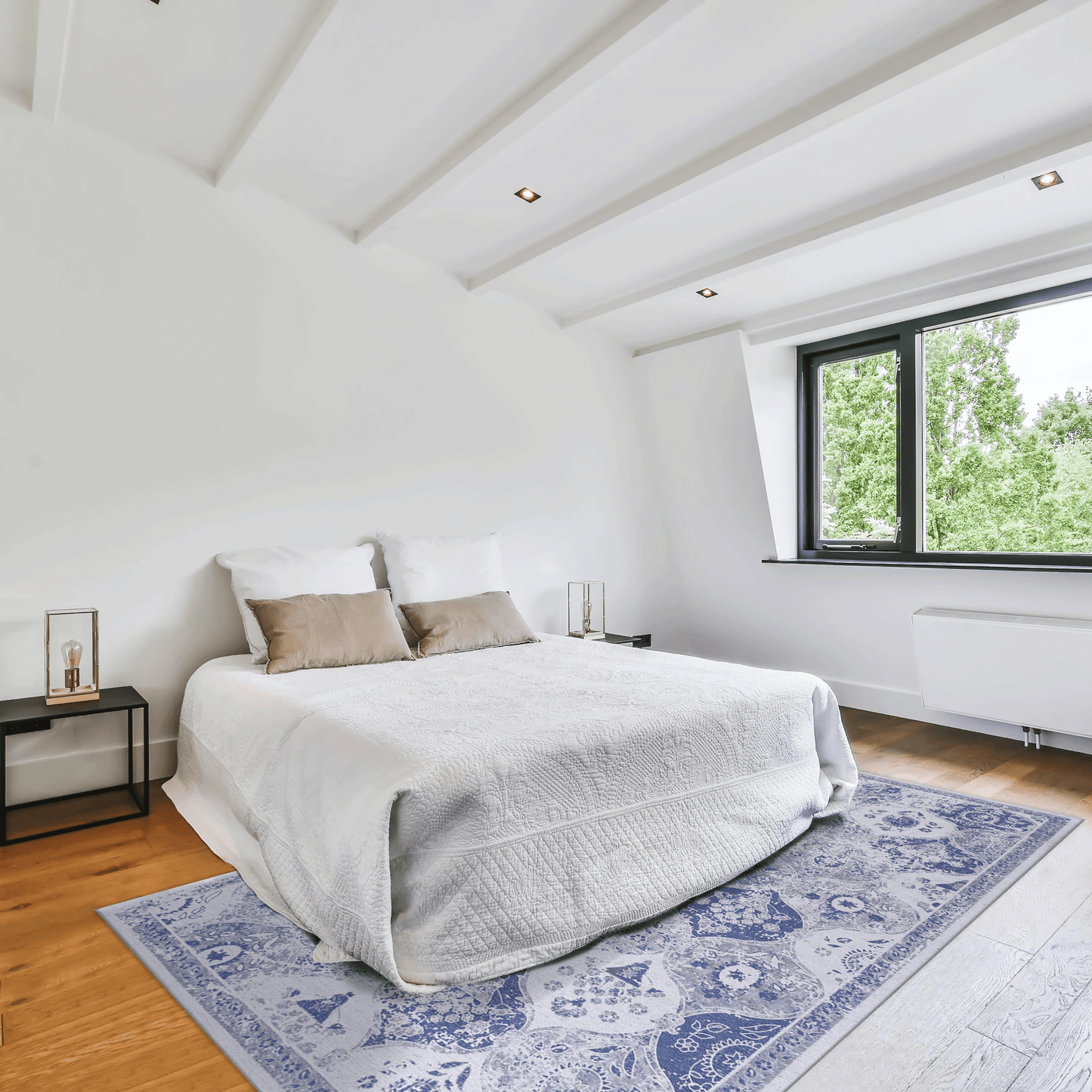 Blue Persian rug with ornate patterns on wooden floor beside a bed