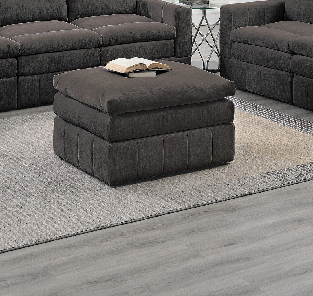 Dark grey upholstered square ottoman with a tufted base used as a coffee table