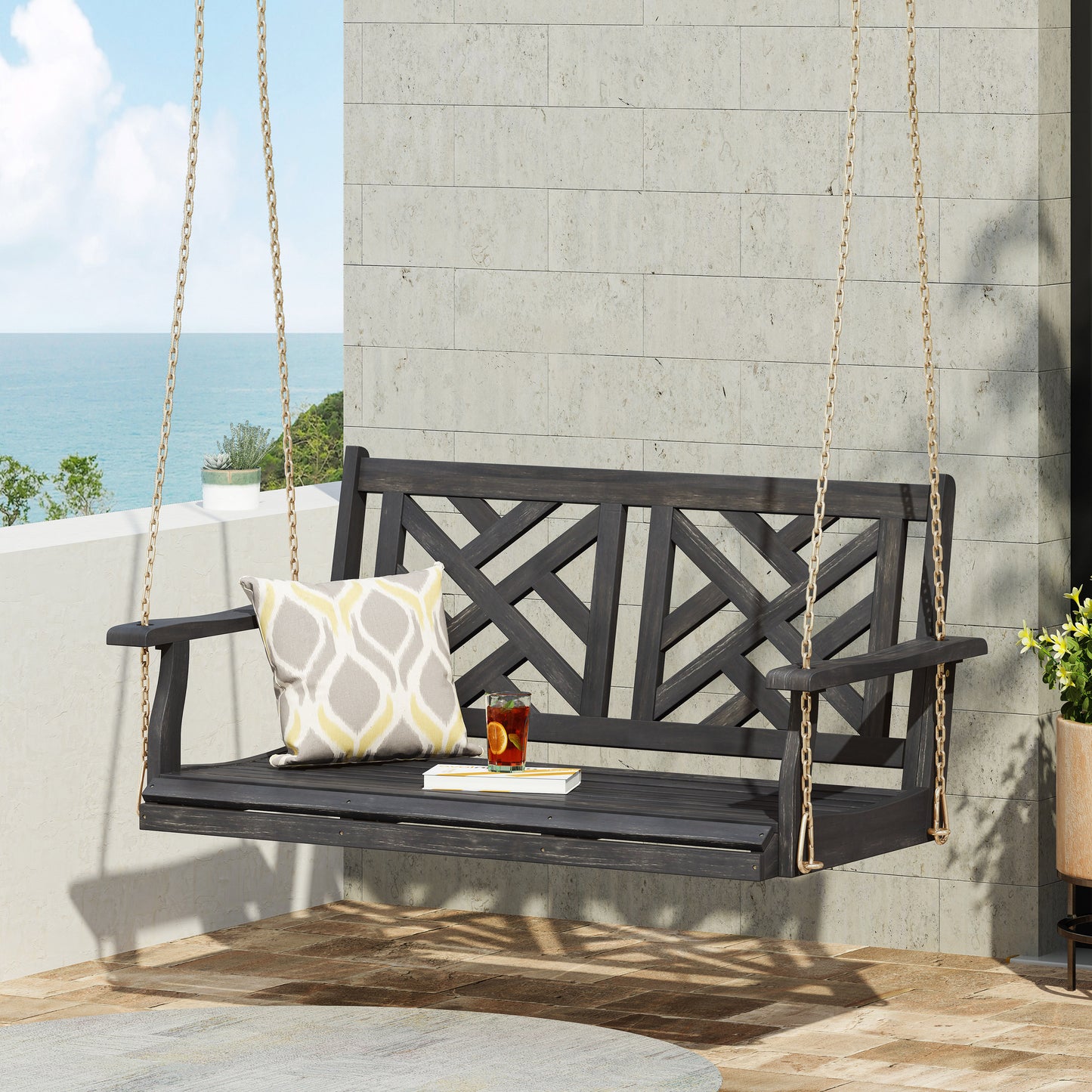 Dark grey wooden porch swing with ornate backrest and gold chains