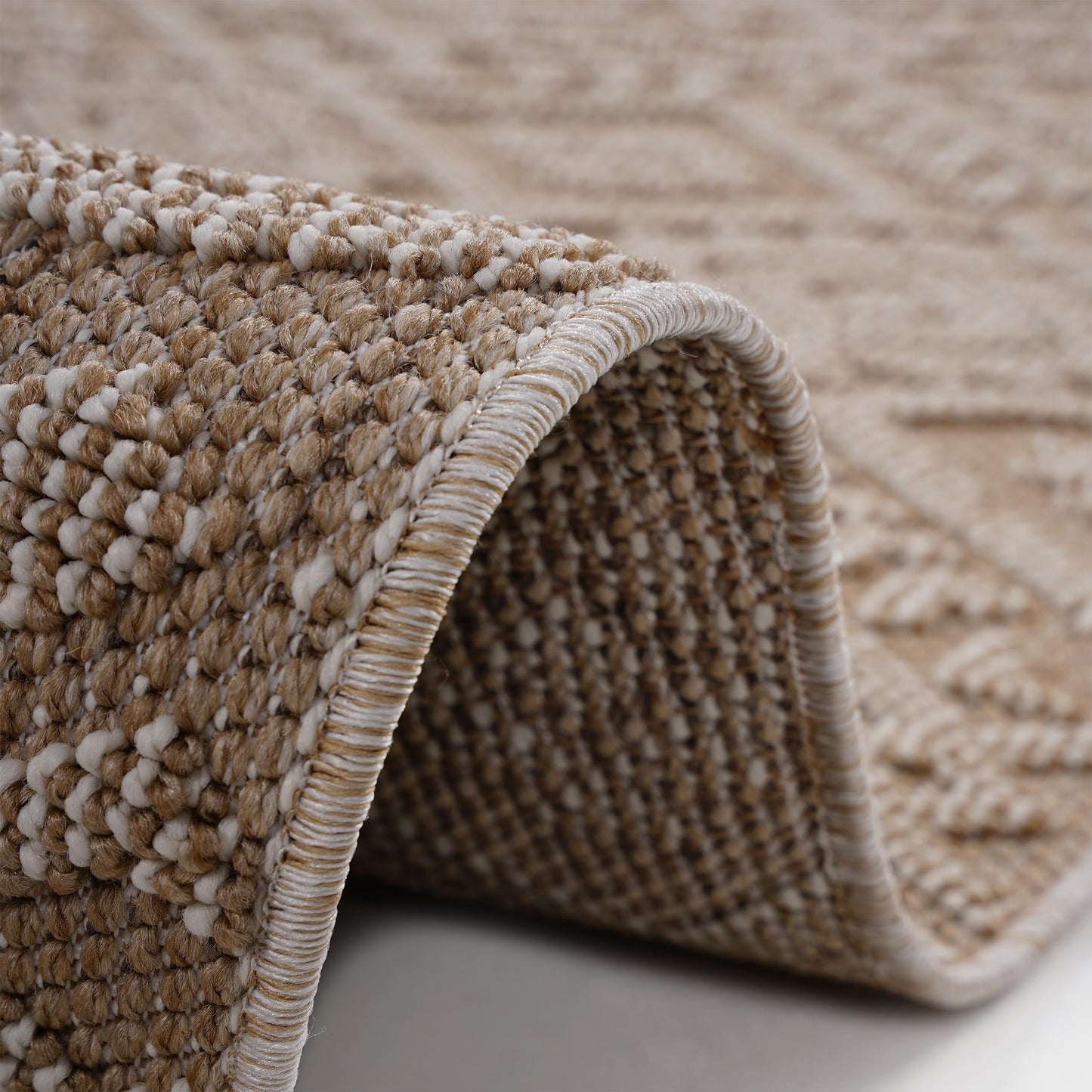Textured beige and white woven rug with diamond pattern detail