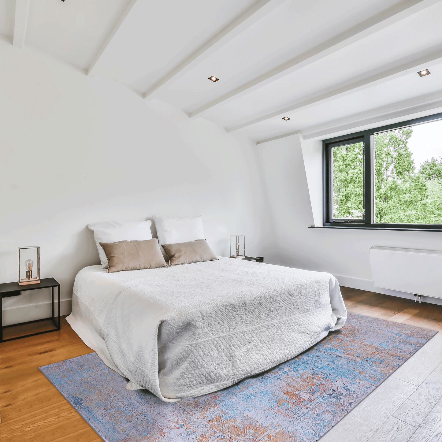 White quilted comforter with beige accent pillows on a bed with a vintageinspired rug