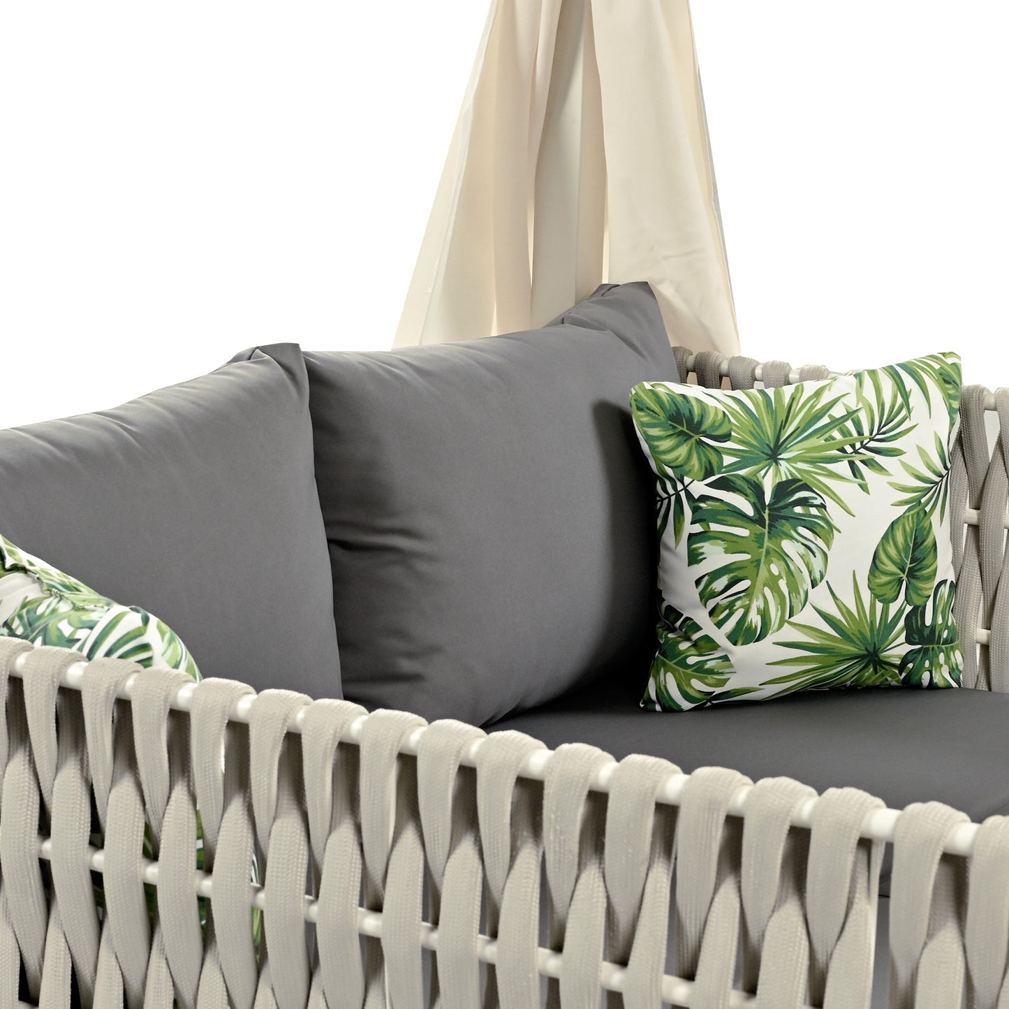 Gray outdoor sofa with tropical leaf print pillows and cream canopy for backyard relaxation