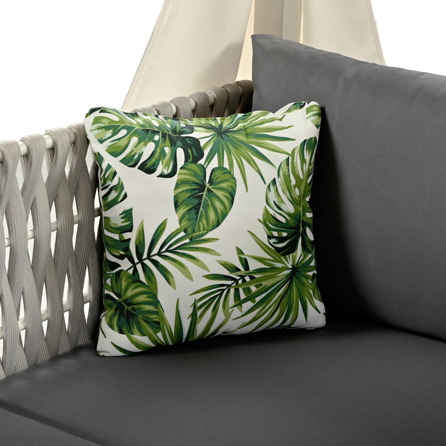 Decorative outdoor pillow with tropical monstera leaf print on white background