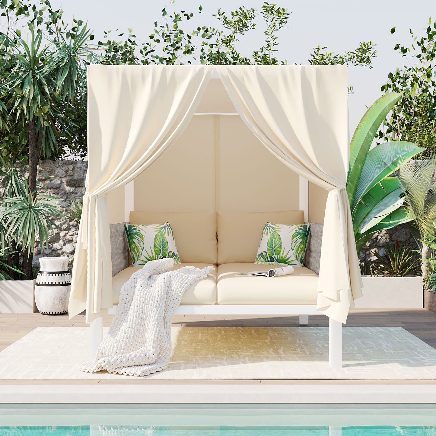Cream canopy daybed with tropical leaf cushions and a chunky knit throw perfect for poolside lounging