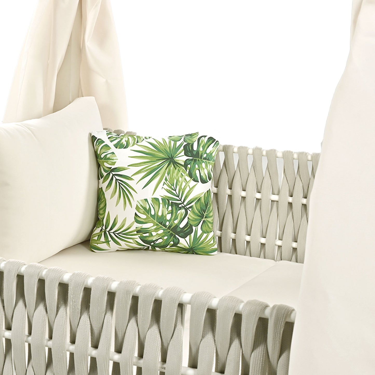 Outdoor swing with plush offwhite cushions and a tropical leaf print accent pillow