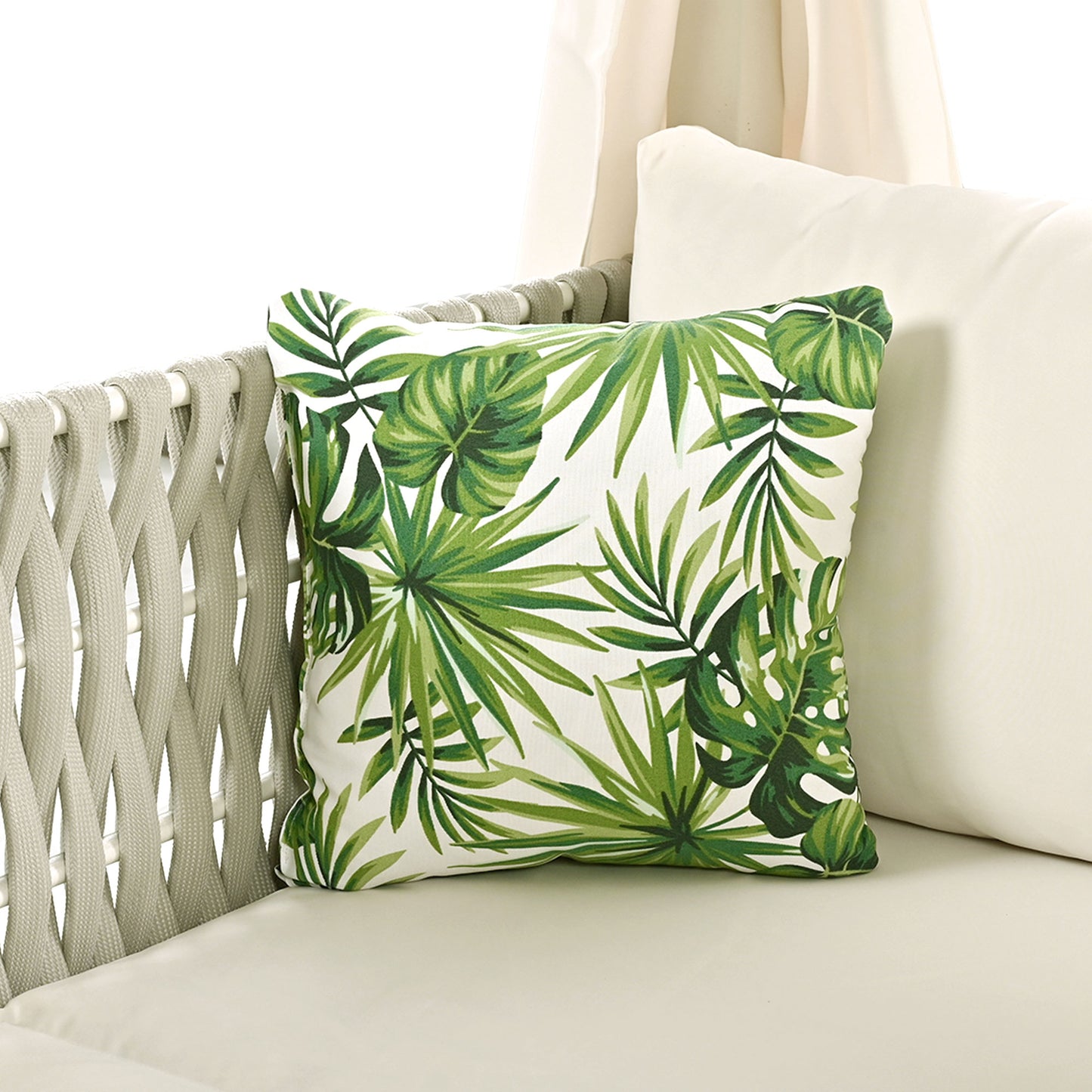 Tropical print throw pillow with lush green leaves on a white background