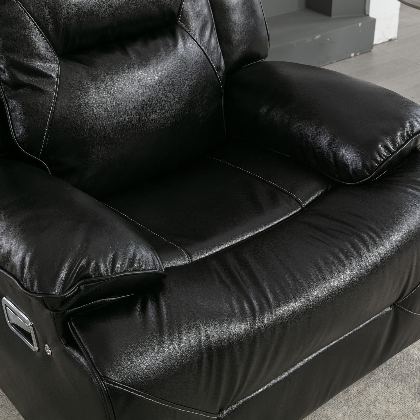 Closeup of plush black leather recliner seat with white stitching detail