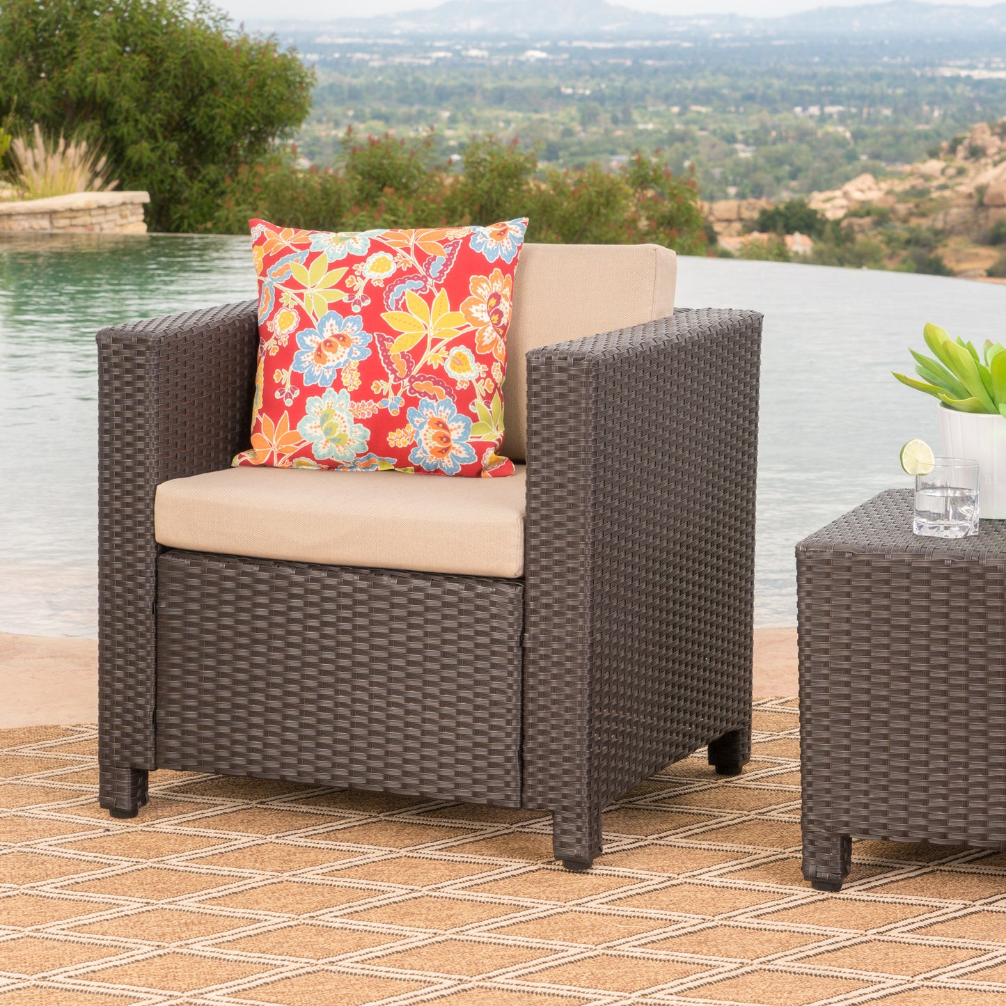 Dark brown rattan armchair with beige cushion and floral pillow outdoors