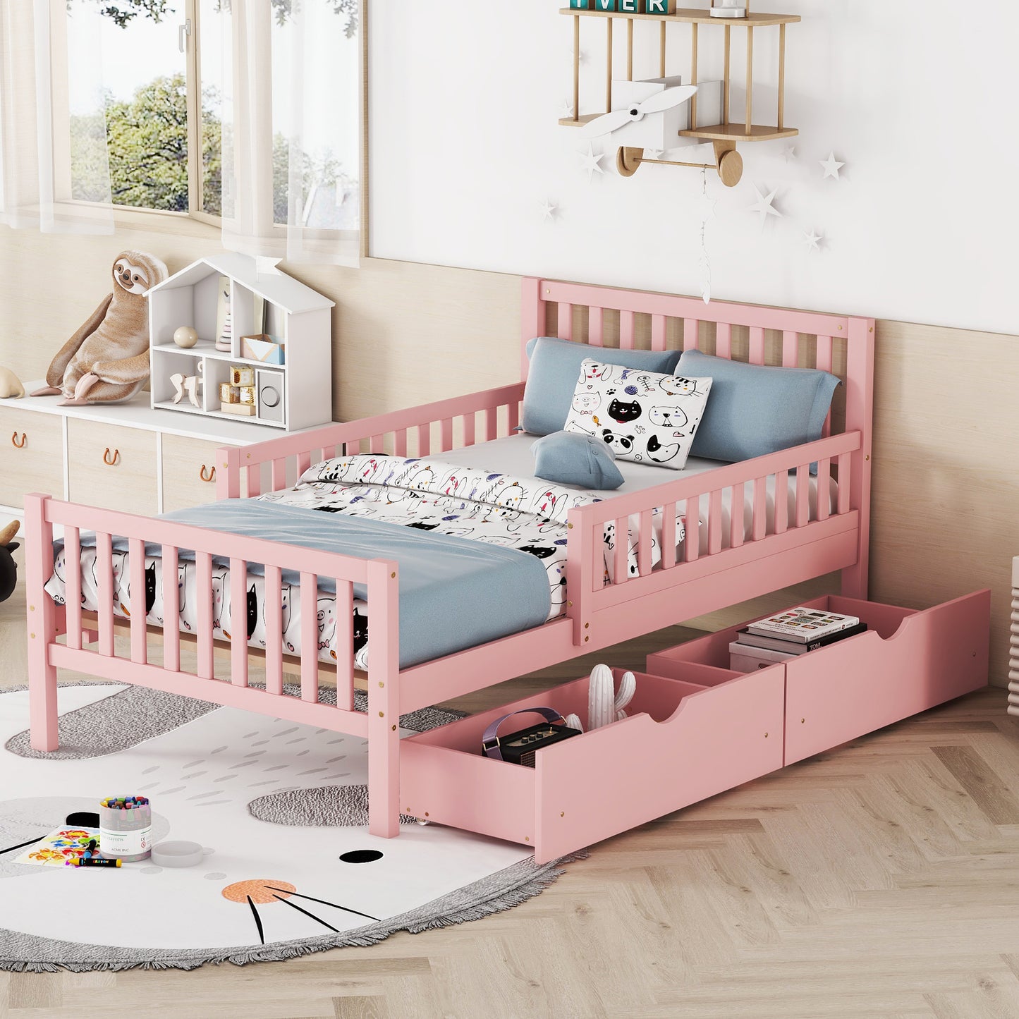 Pink wooden toddler bed with drawers and playful bedding