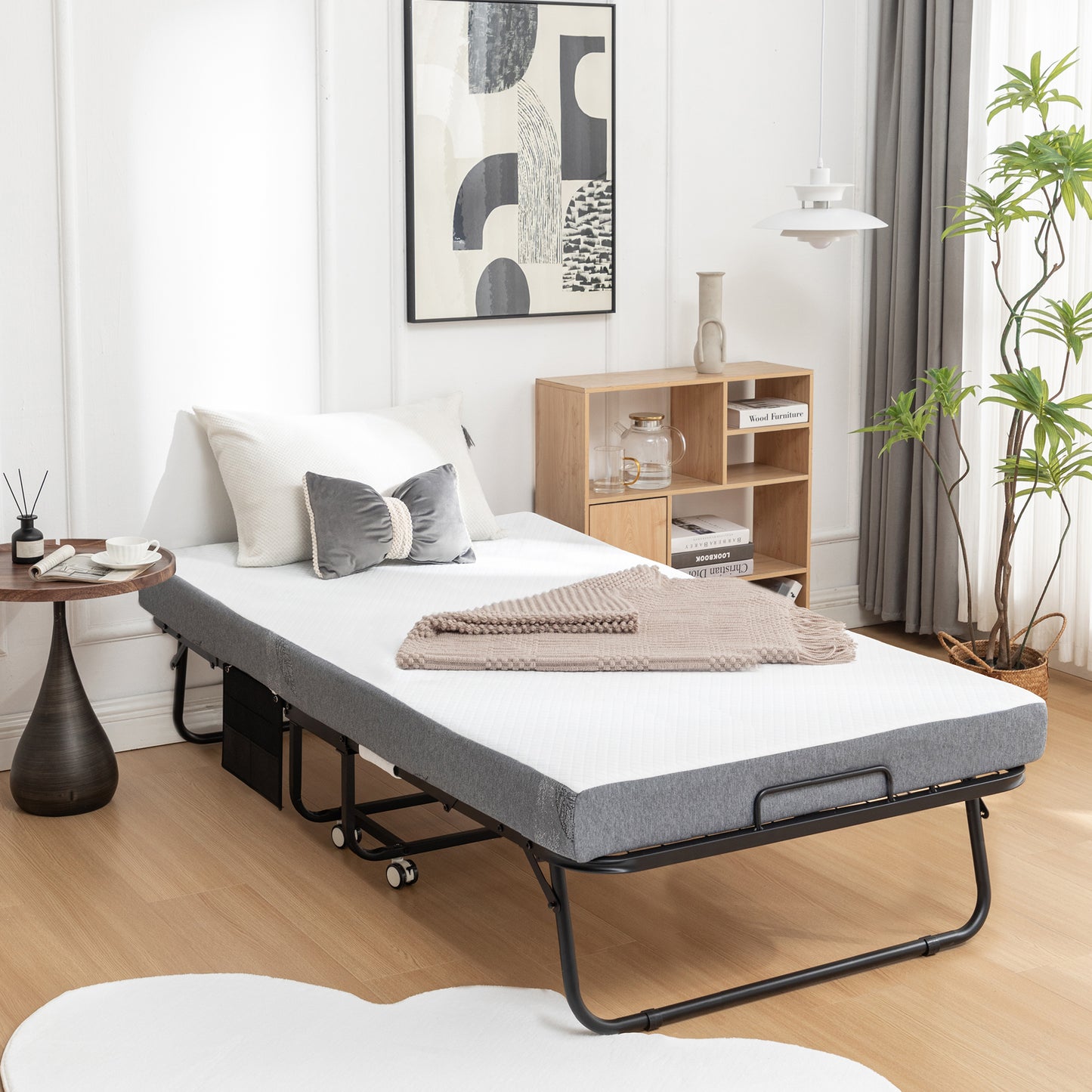 Gray folding bed with white mattress and beige throw blanket