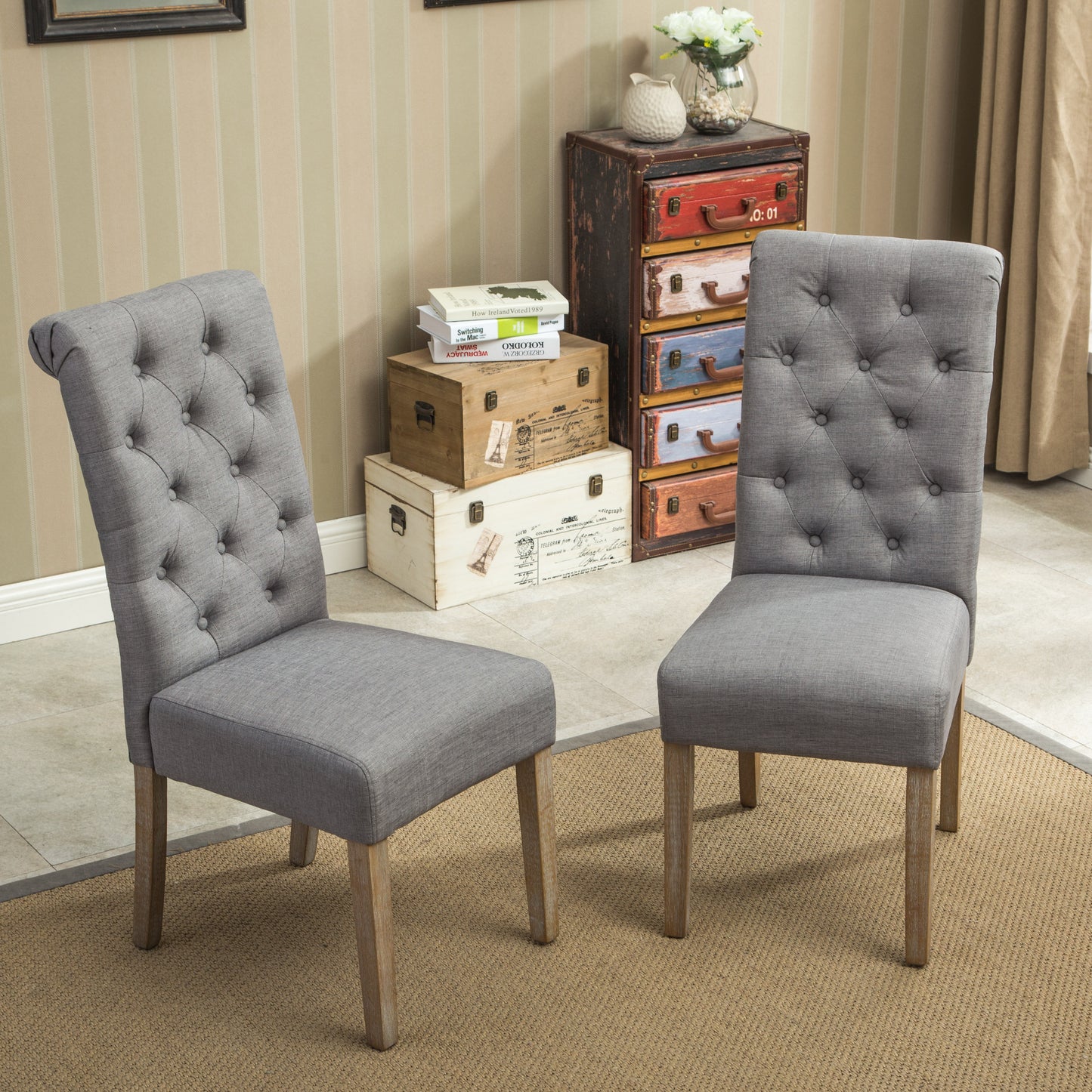Two grey upholstered dining chairs with diamond tufting and natural wood legs