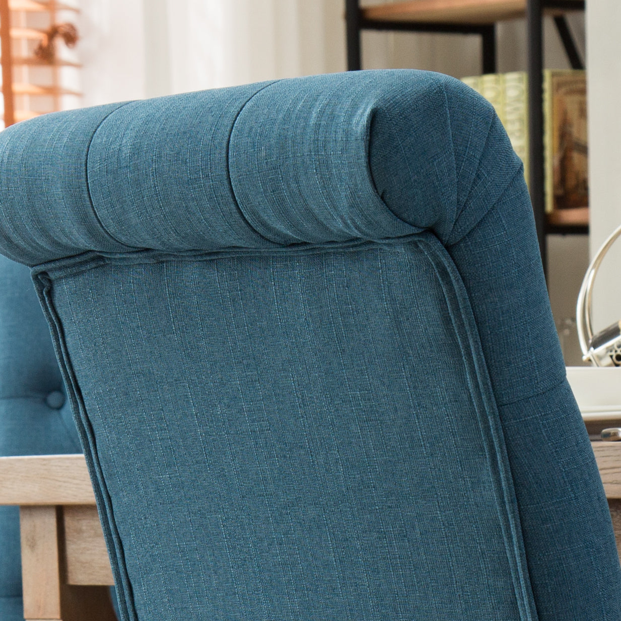 Tufted teal fabric armchair backrest with elegant rolltop detail