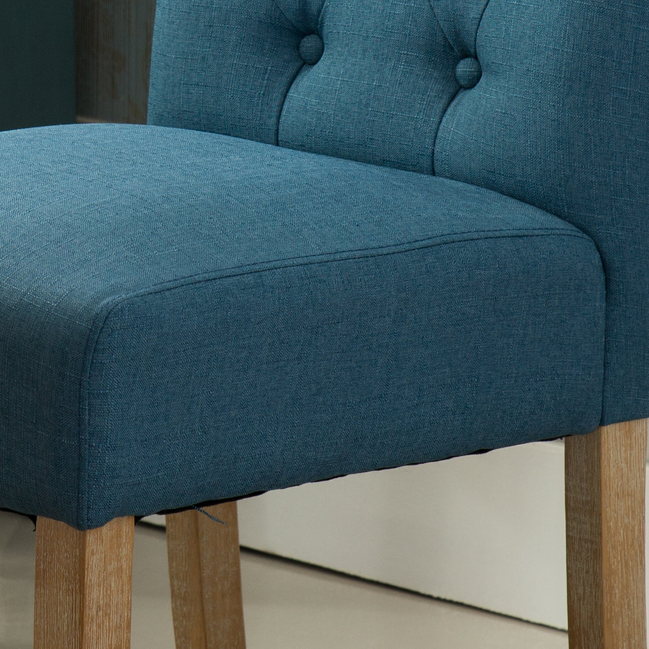 Teal upholstered dining chair with tufted back and wooden legs