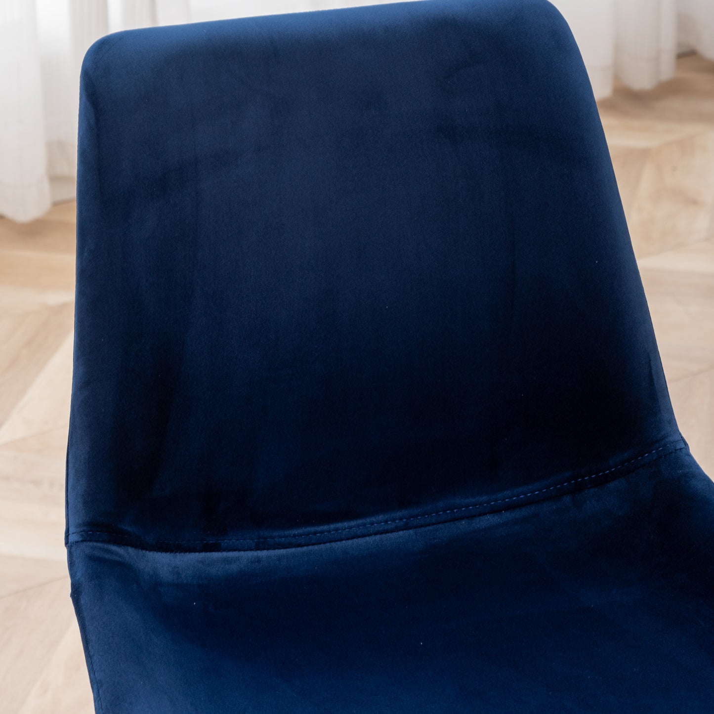 Closeup of a plush navy blue velvet dining chair seat with subtle stitching detail