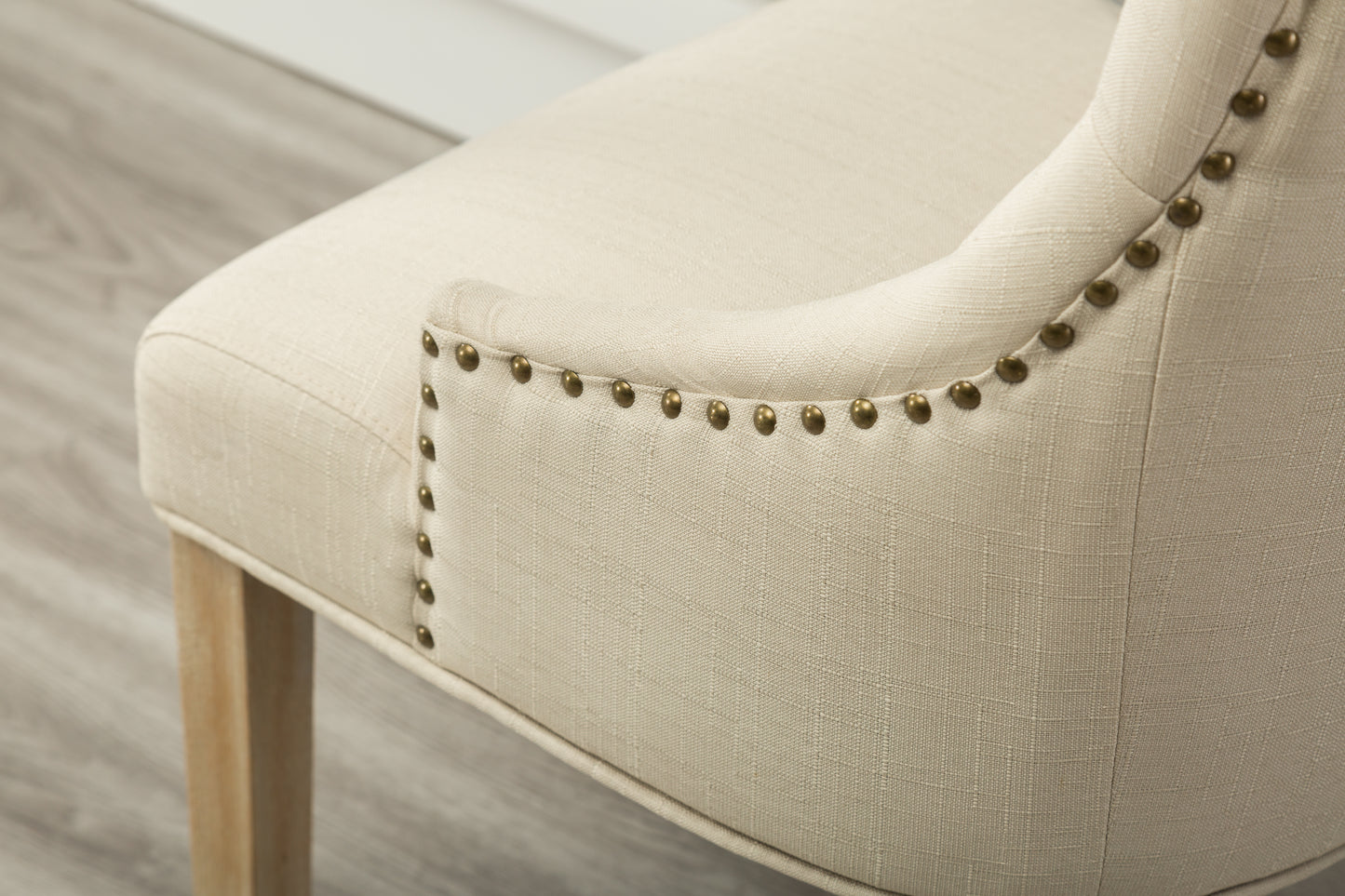 Cream linen accent chair with brass nailhead trim and wooden legs