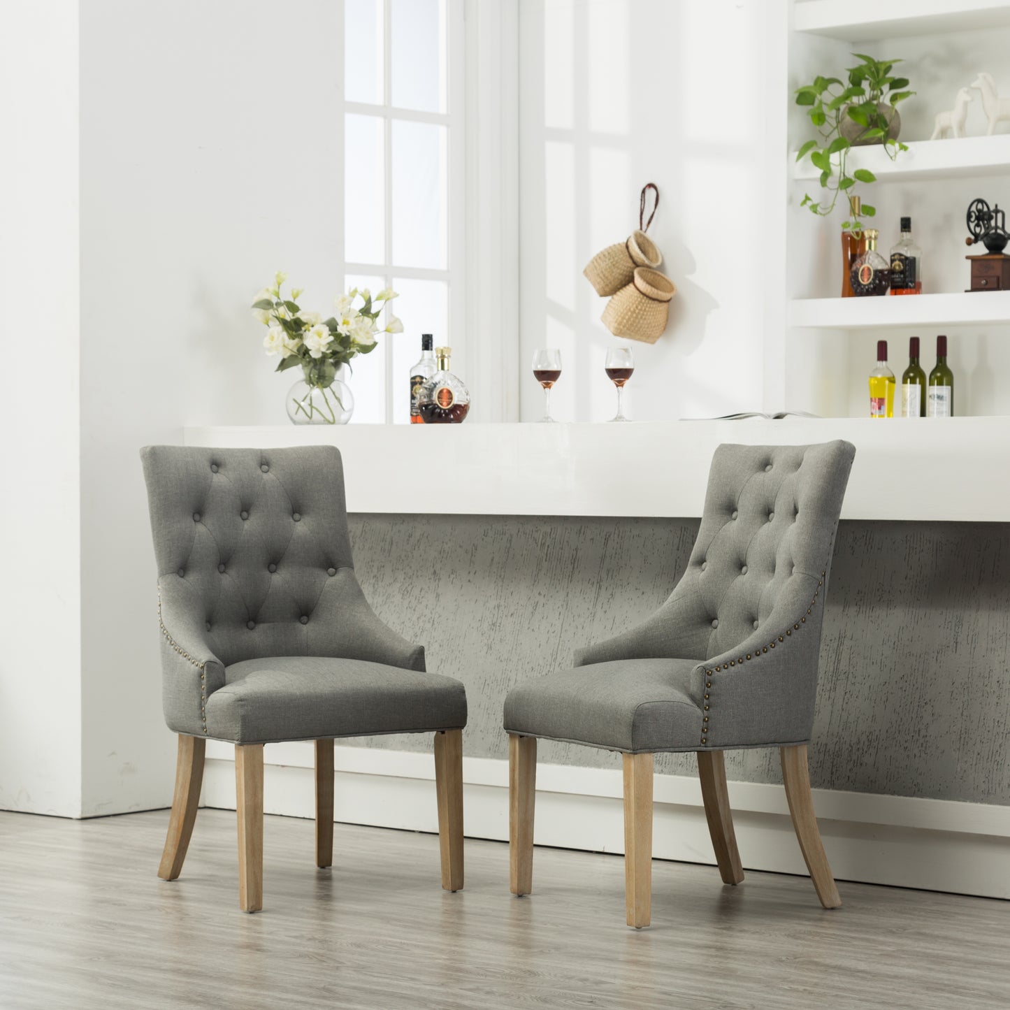 Tufted gray fabric dining chair with antique brass nailhead trim and oak legs