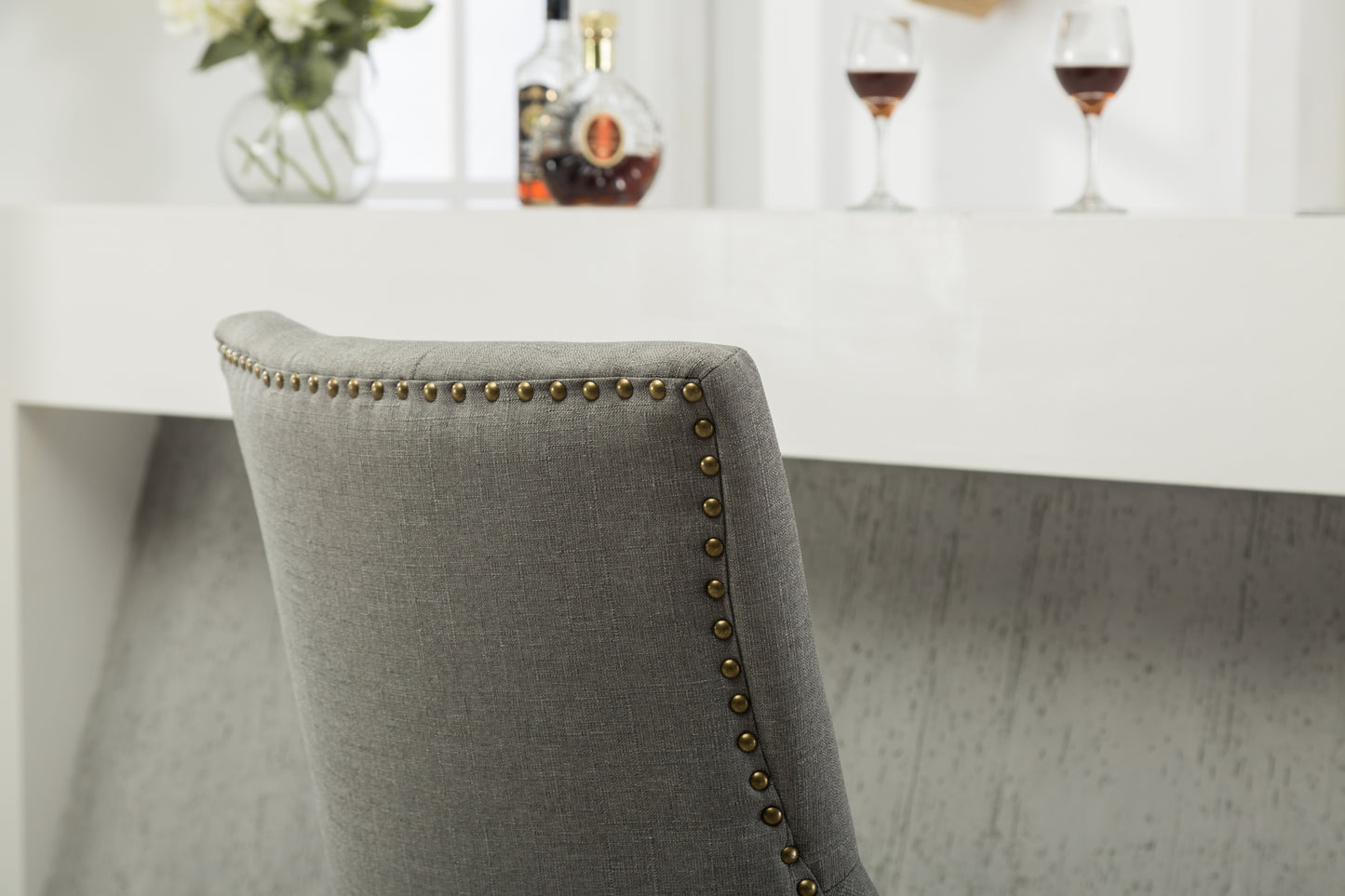 Grey linen upholstered bar stool with decorative brass nailhead trim