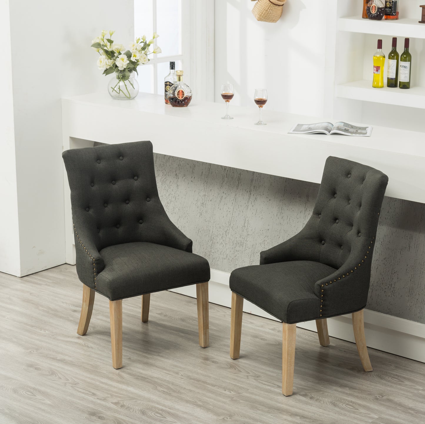 Dark grey upholstered dining chair with button tufting and brass nailhead trim accents