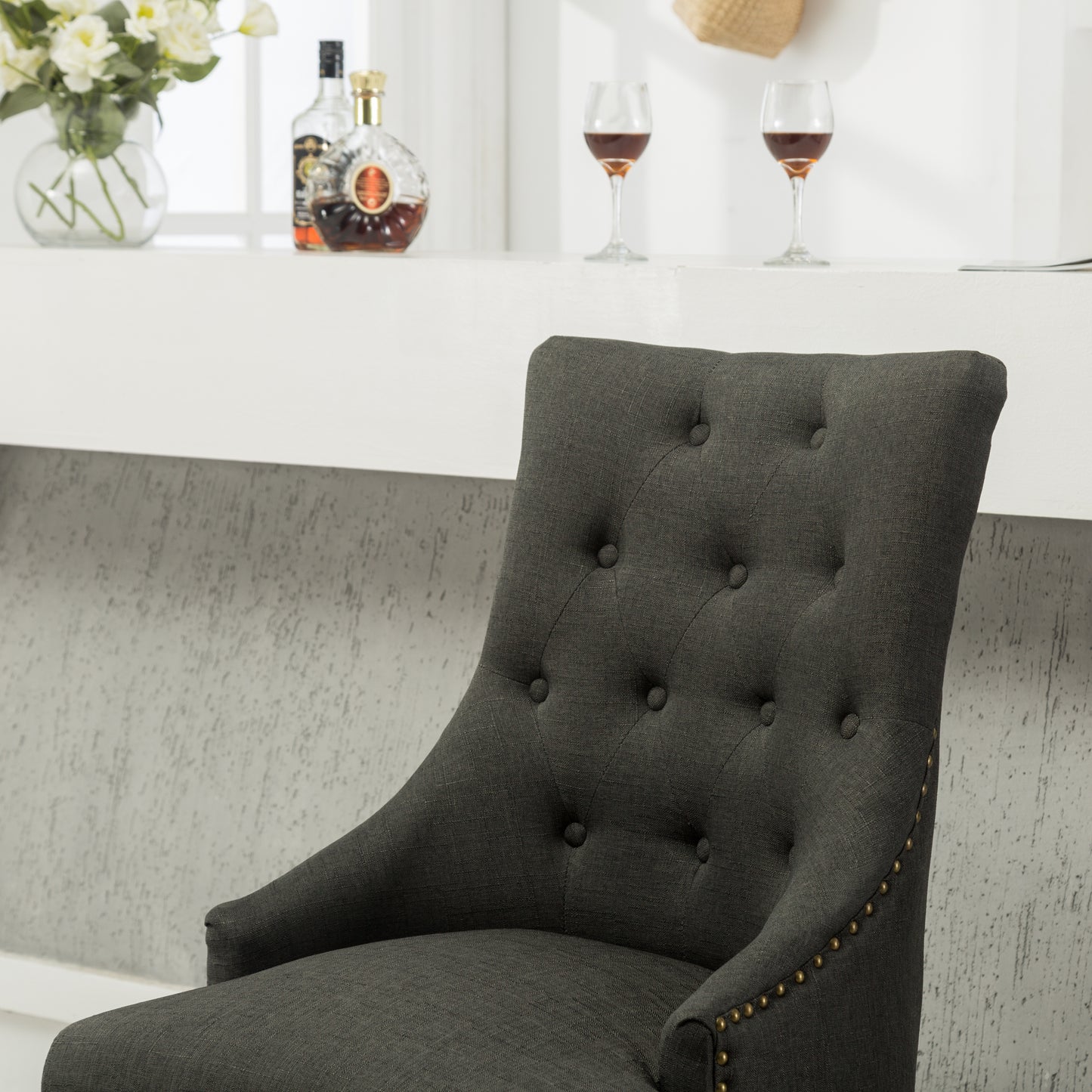 Dark grey fabric upholstered dining chair with tufted backrest and brass nailhead trim