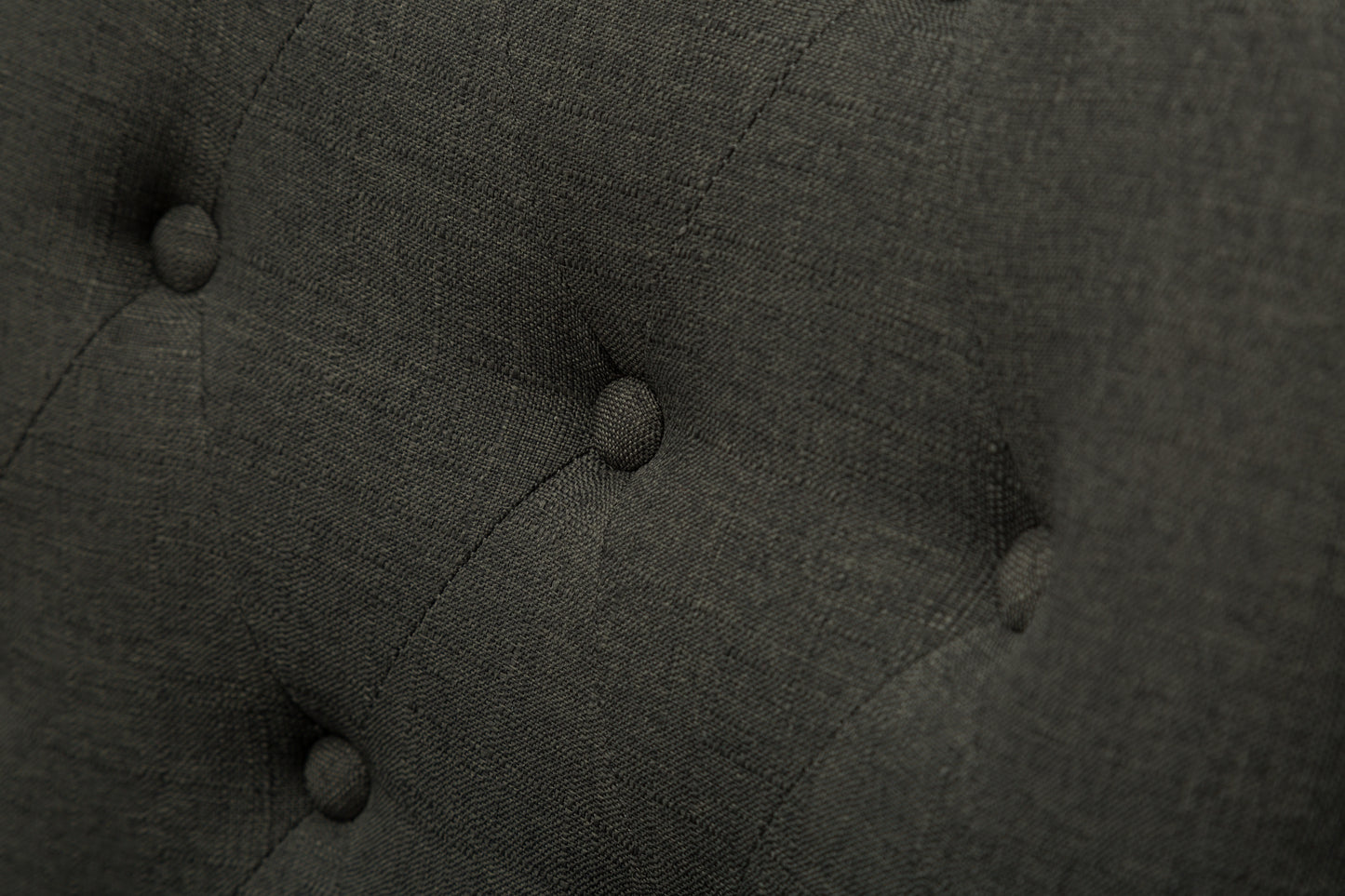 Closeup of dark grey textured fabric with diamond tufting detail
