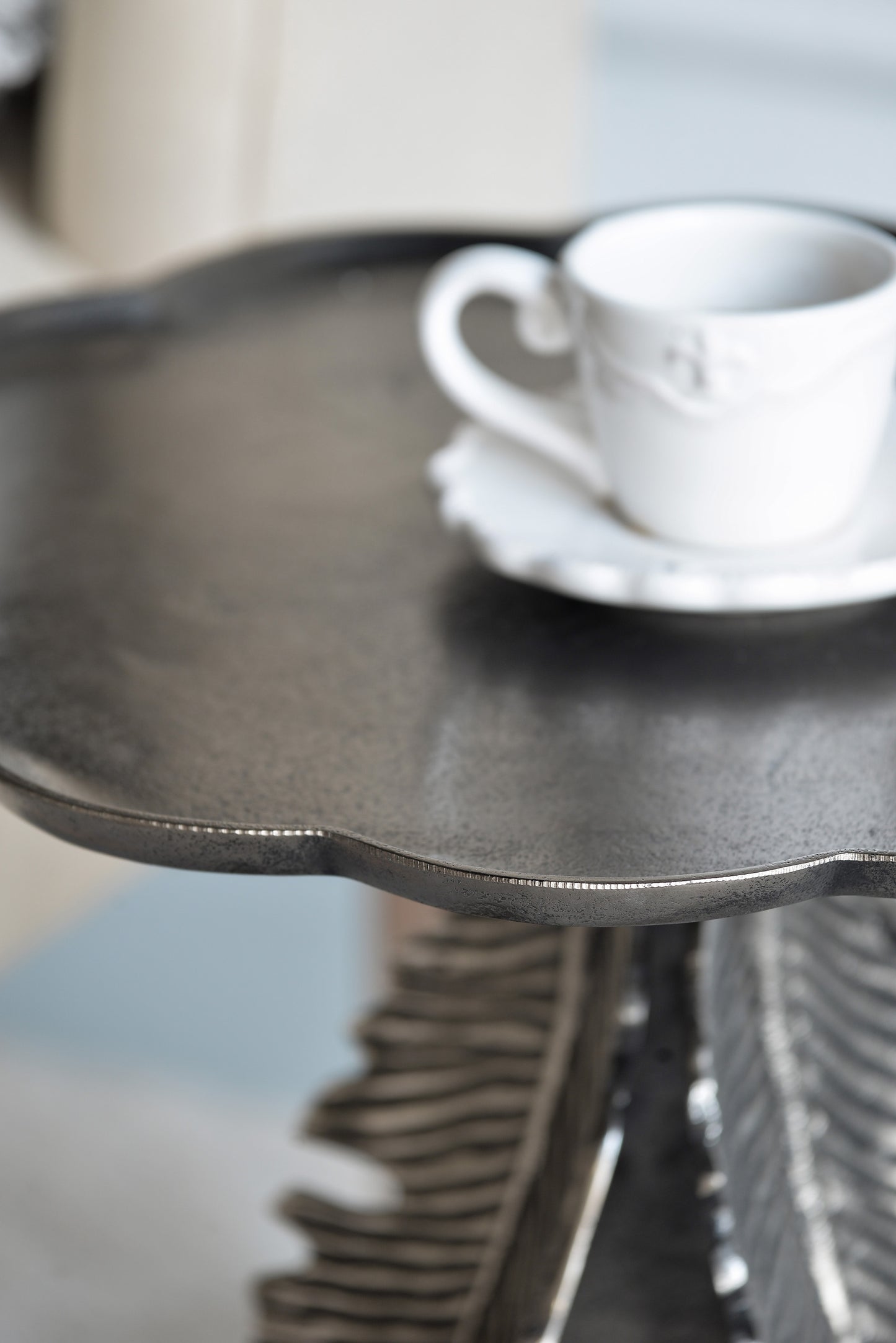 Ornate metal accent table with a grey textured top and sculpted base