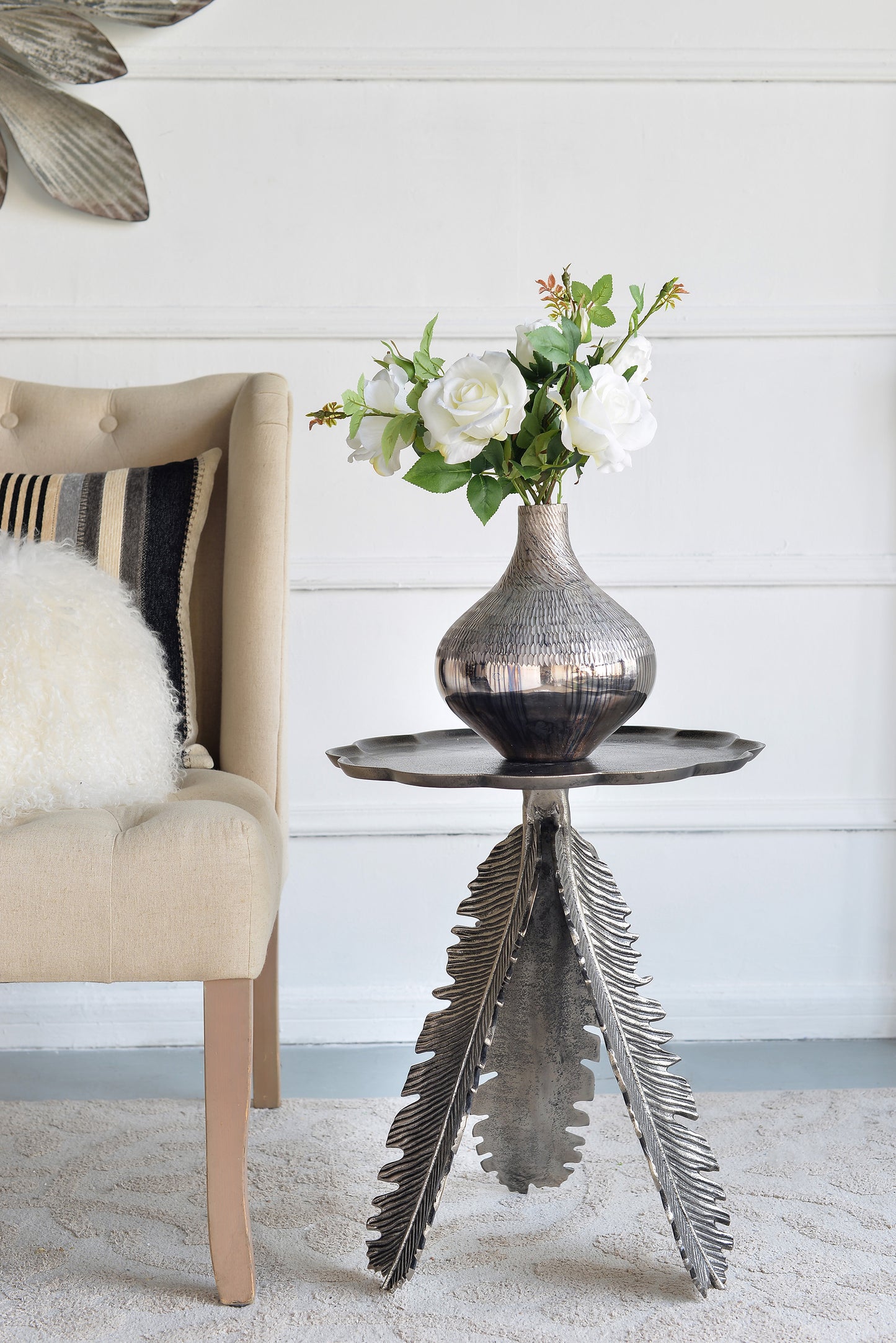 Elegant silver leaf side table featuring a textured metallic vase with white roses