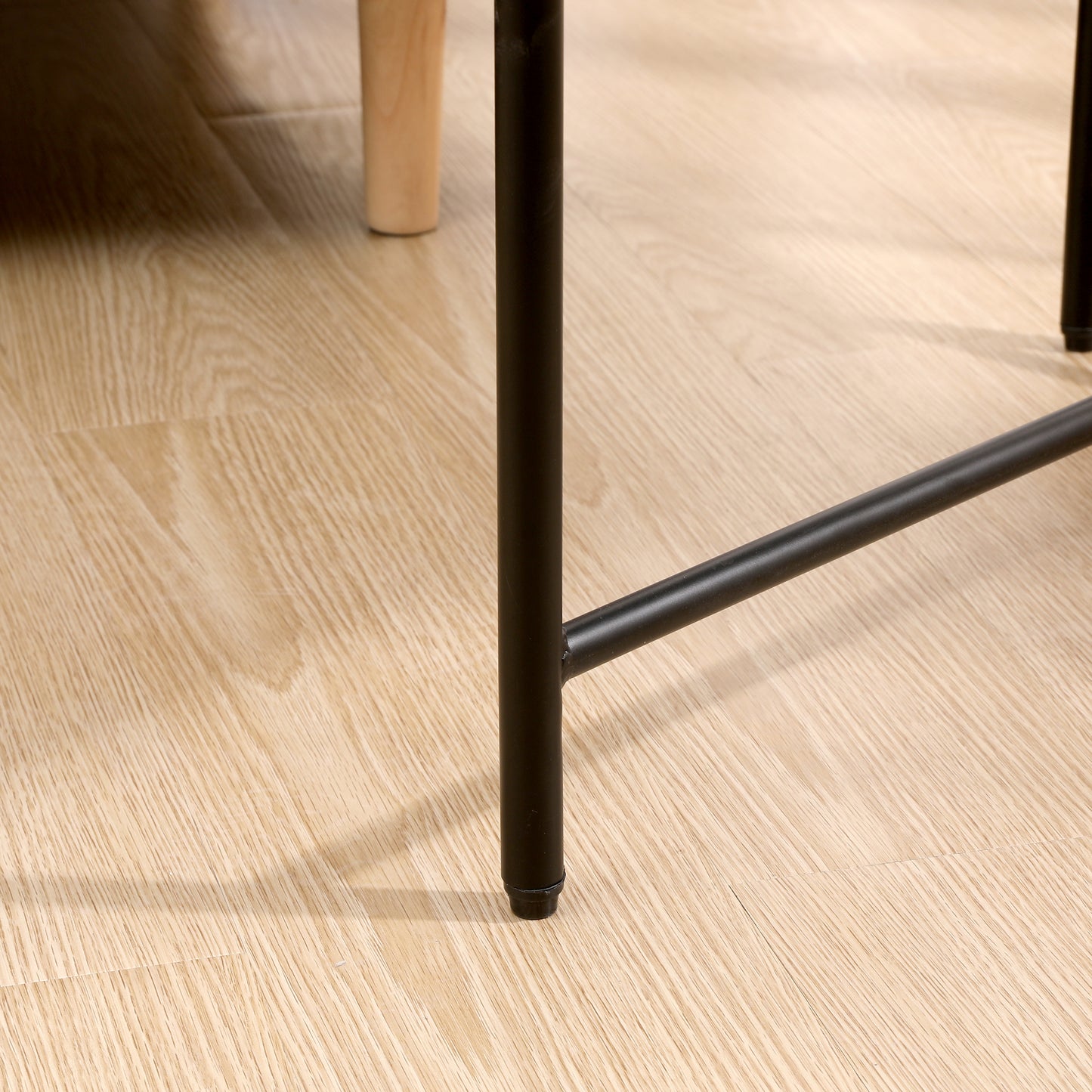 Black metal table leg with wooden floor detail