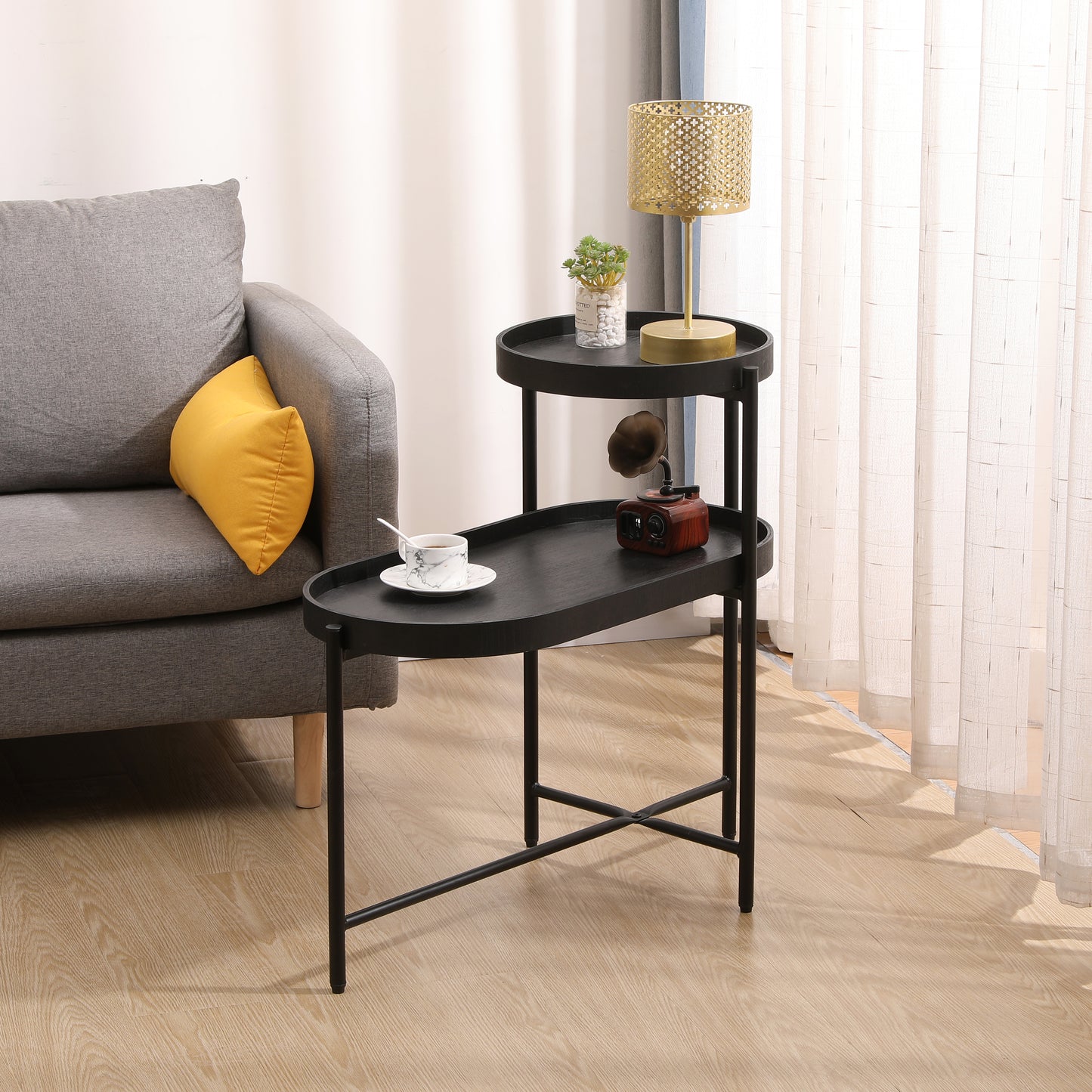 Black metal tiered side table with oval trays holding decorative items