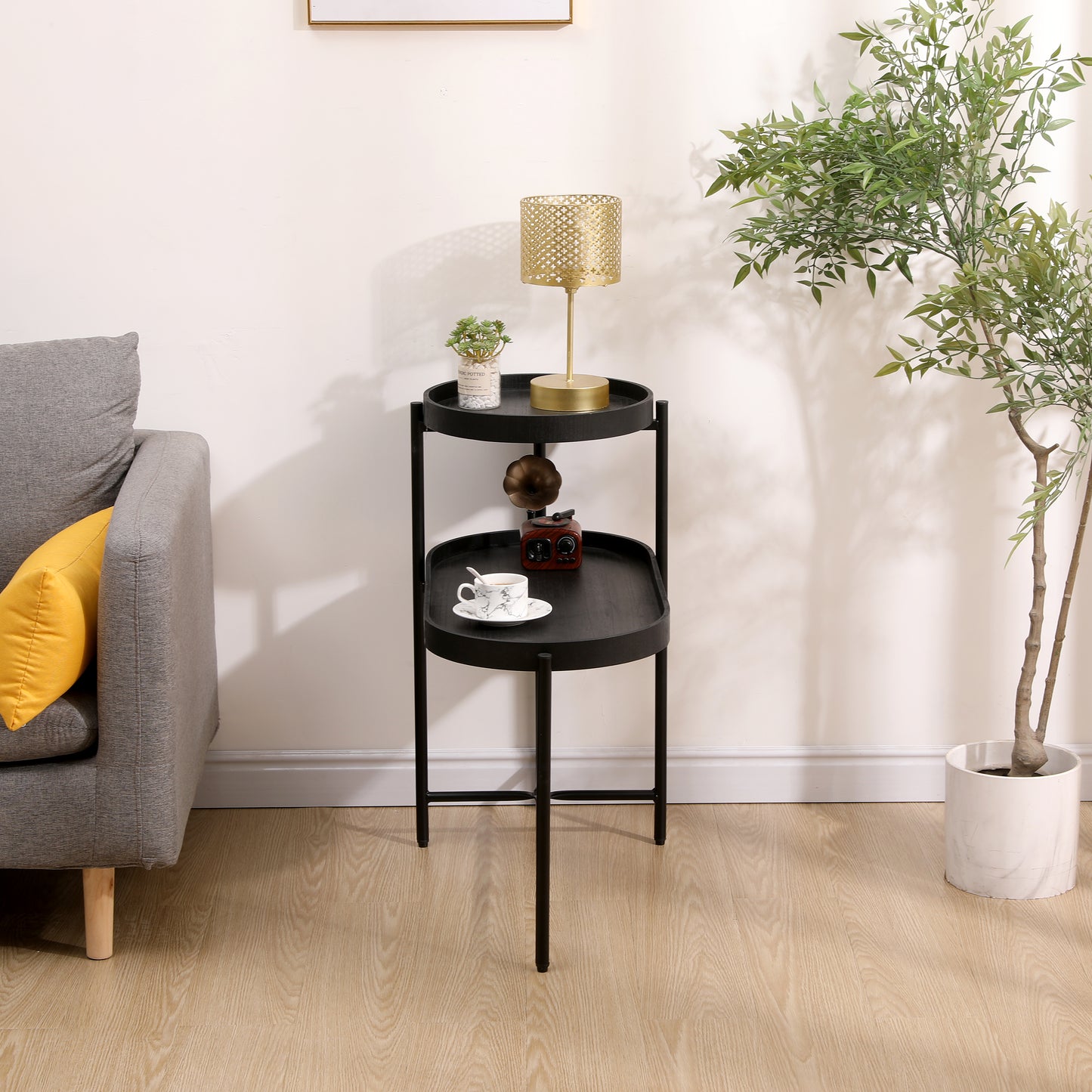 Black metal twotier side table with a gold lamp and cup of coffee