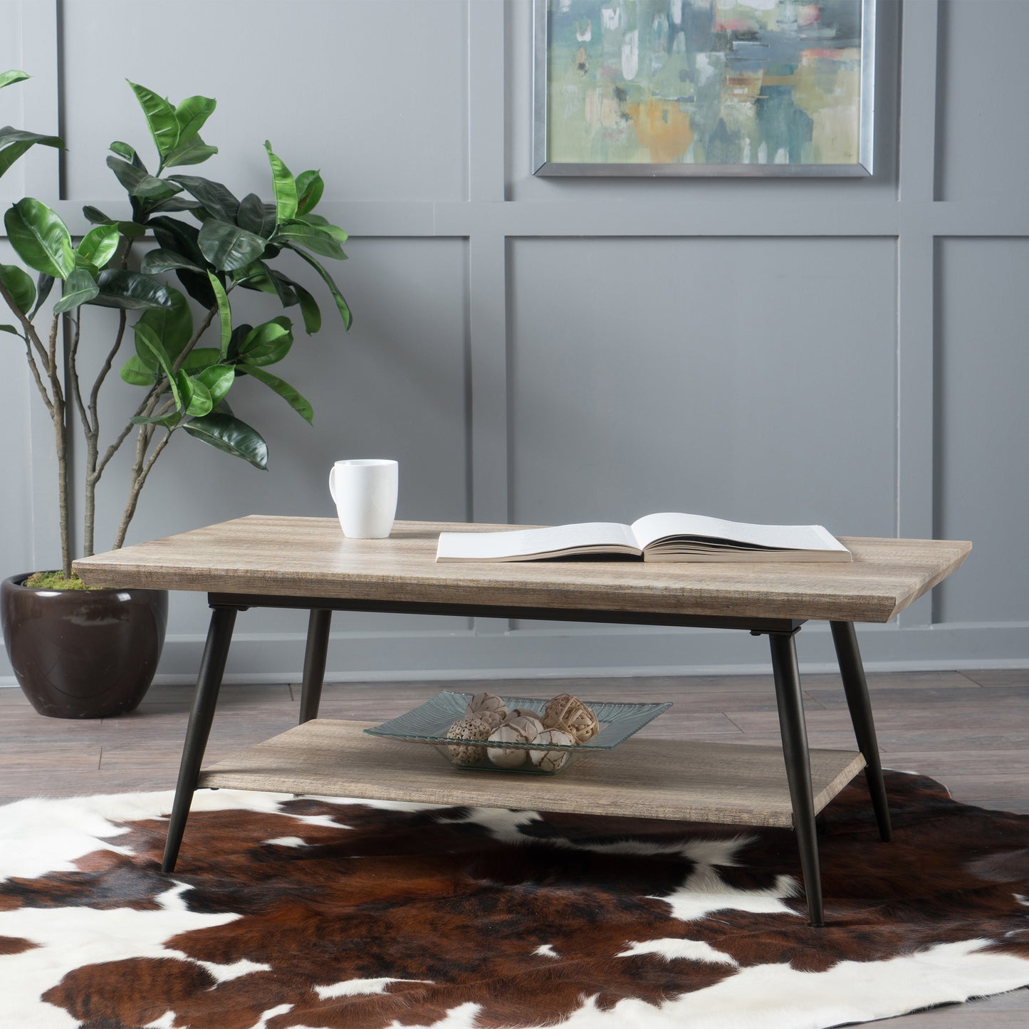 Rustic wood coffee table with black metal legs and a lower shelf holding a book and cup