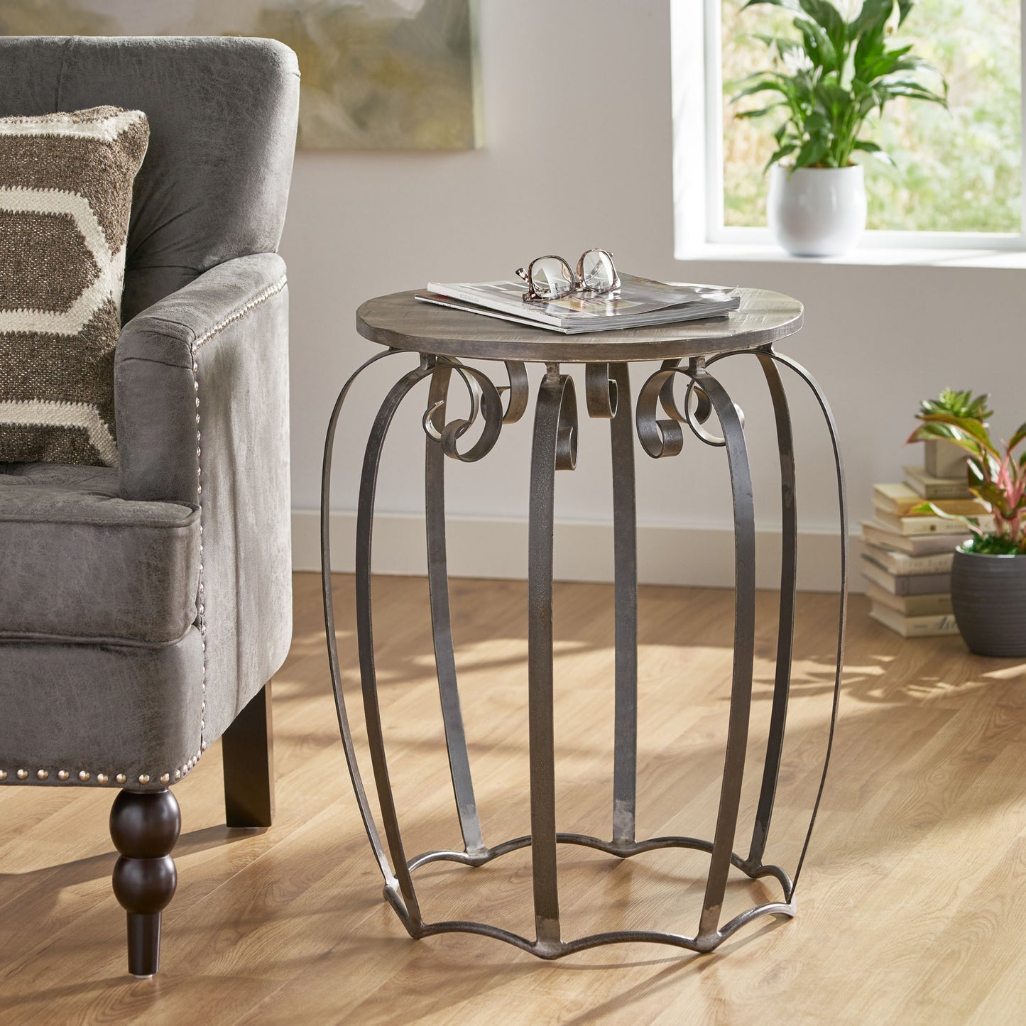Rustic round metal side table with weathered wood top and ornate scroll legs