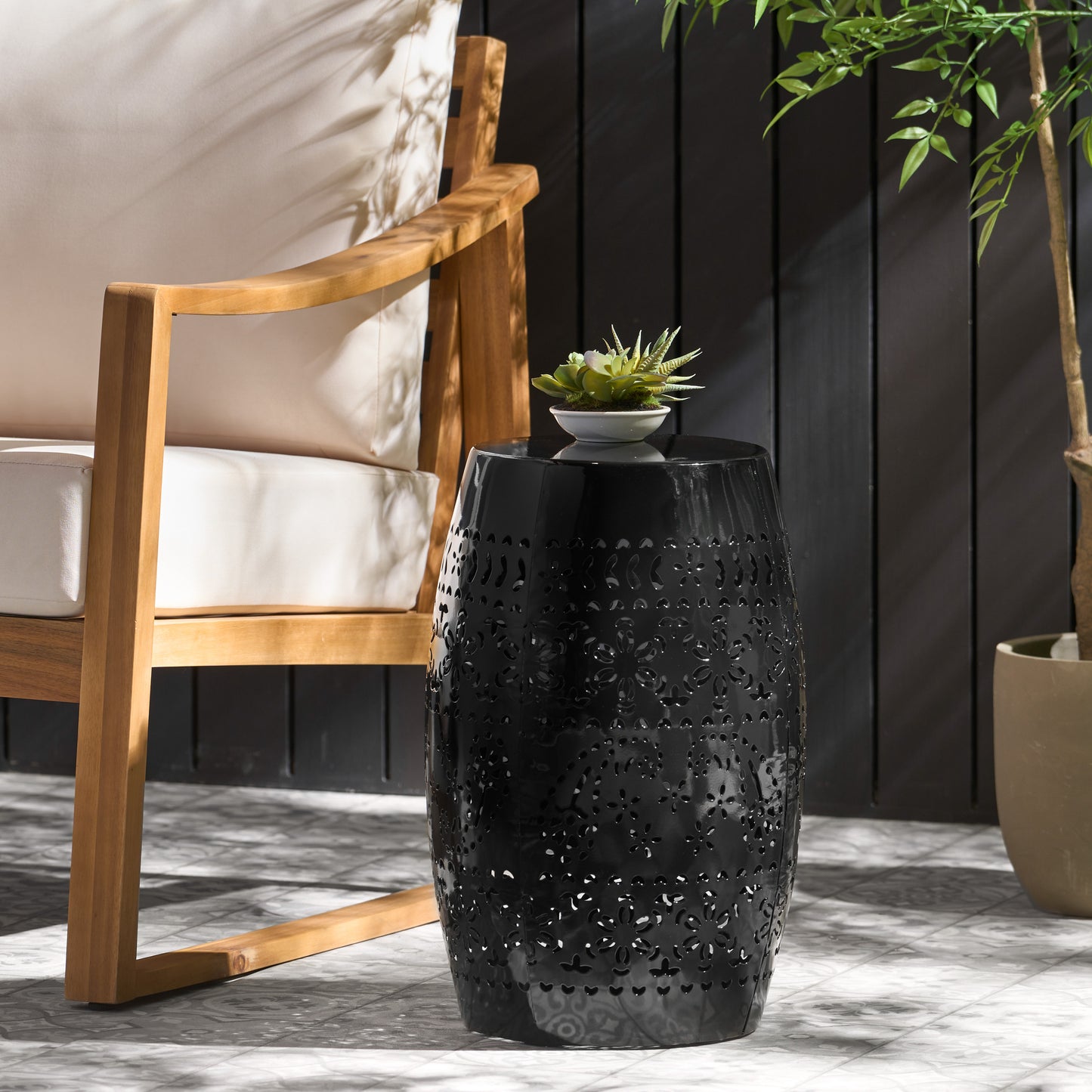 Black ceramic garden stool with intricate floral cutouts ideal for outdoor seating