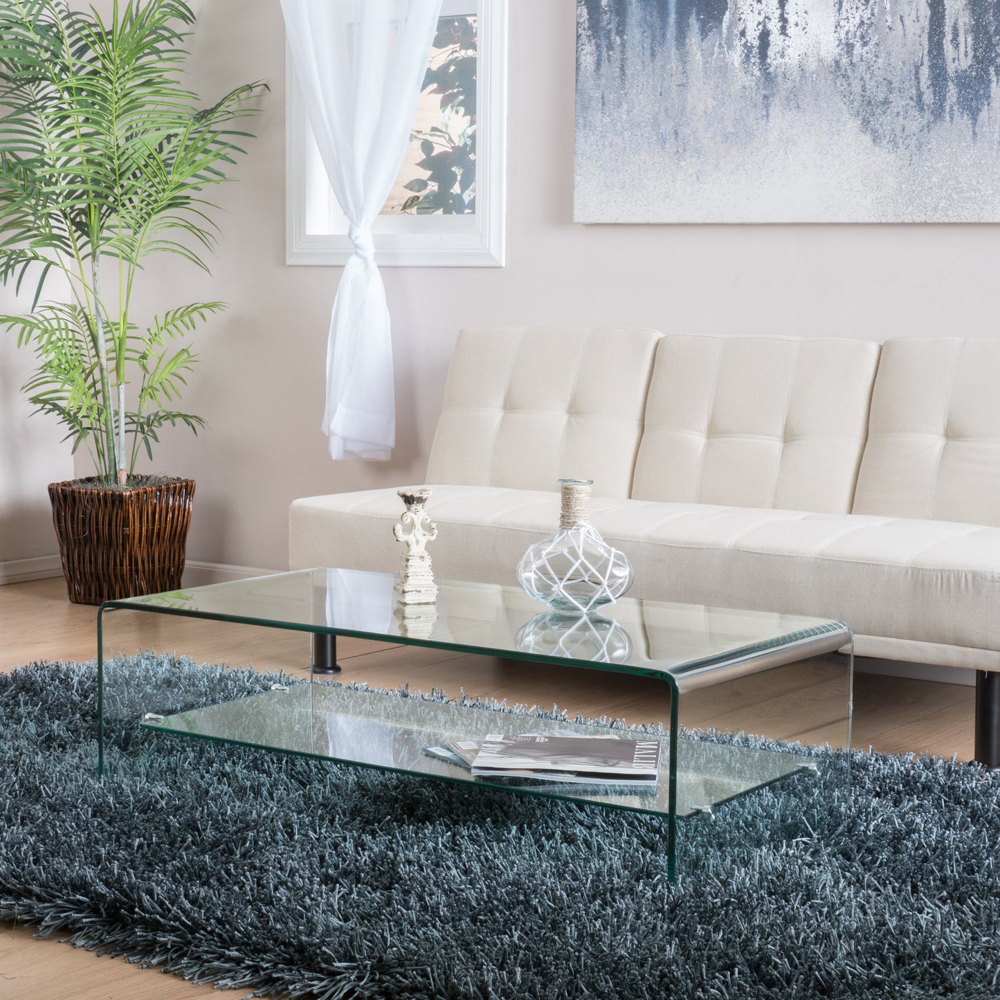 Curved clear glass coffee table with modern design on shaggy gray rug