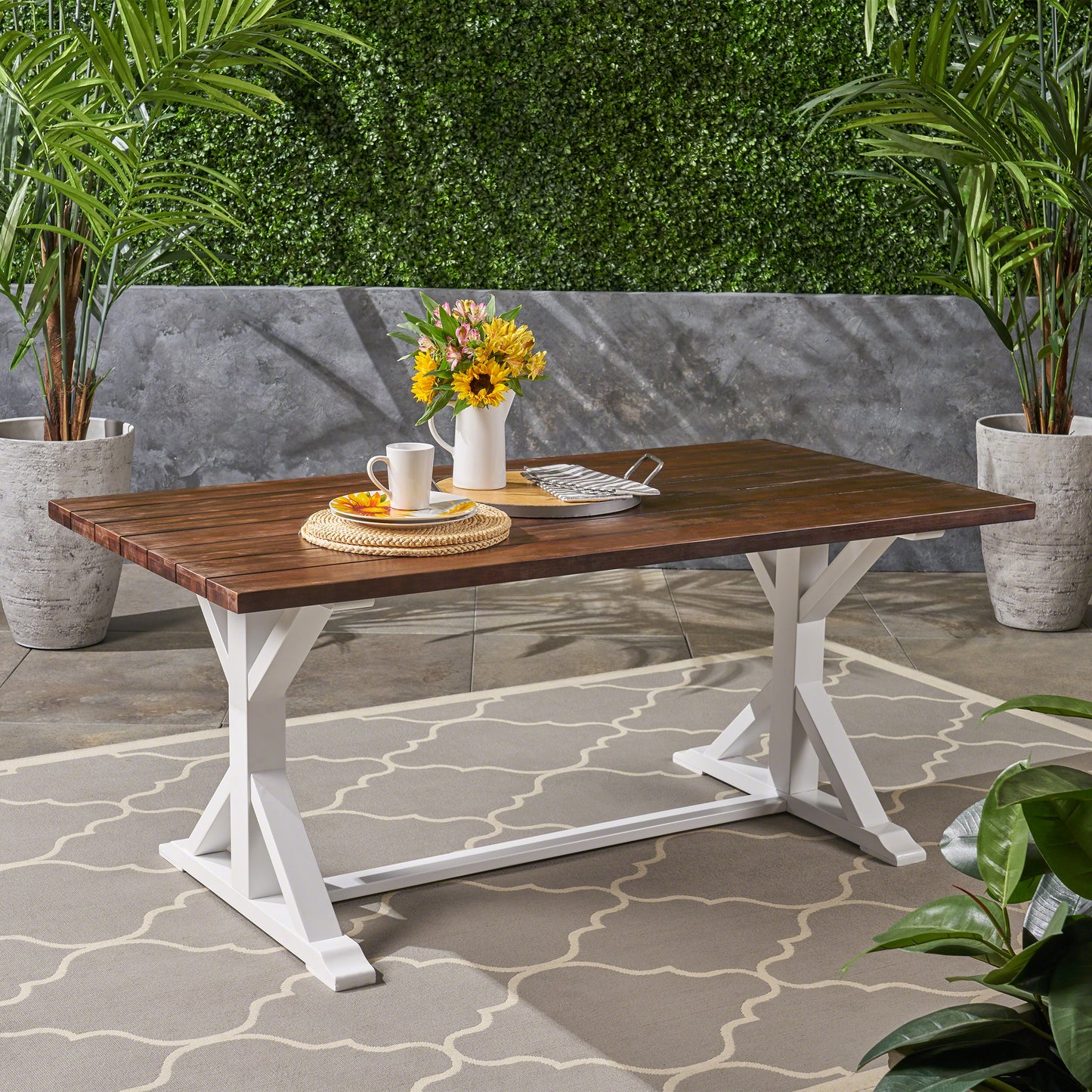 Dark wood farmhouse dining table with white trestle legs on outdoor patio