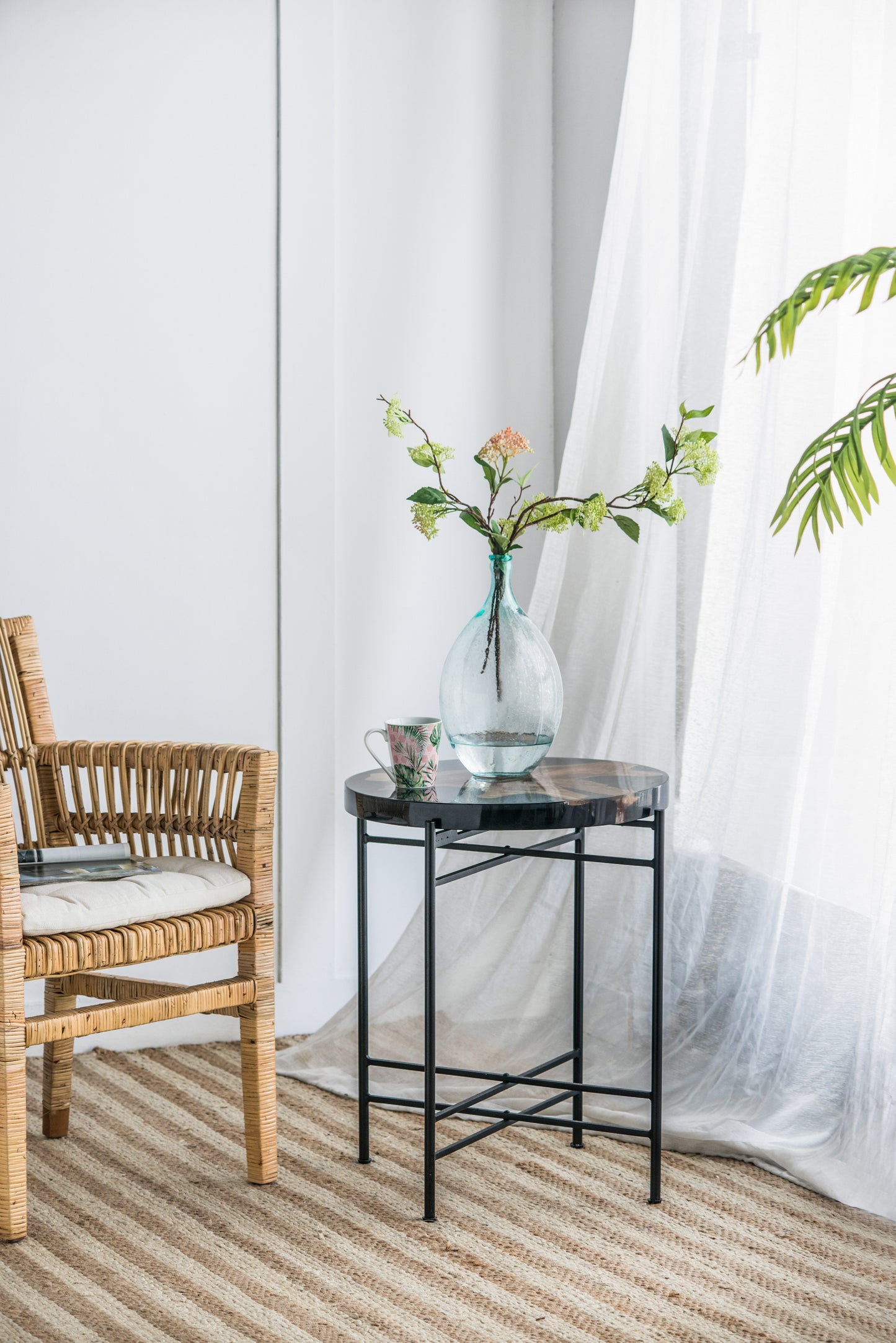 Woven rattan armchair with cream cushion and magazines natural fiber rug