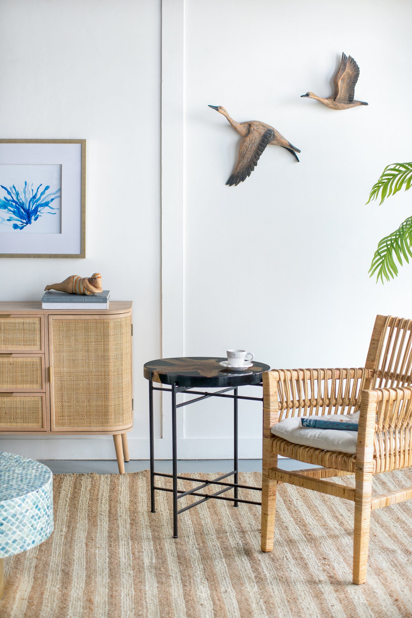 Woven rattan accent chair with striped seat cushion and a book